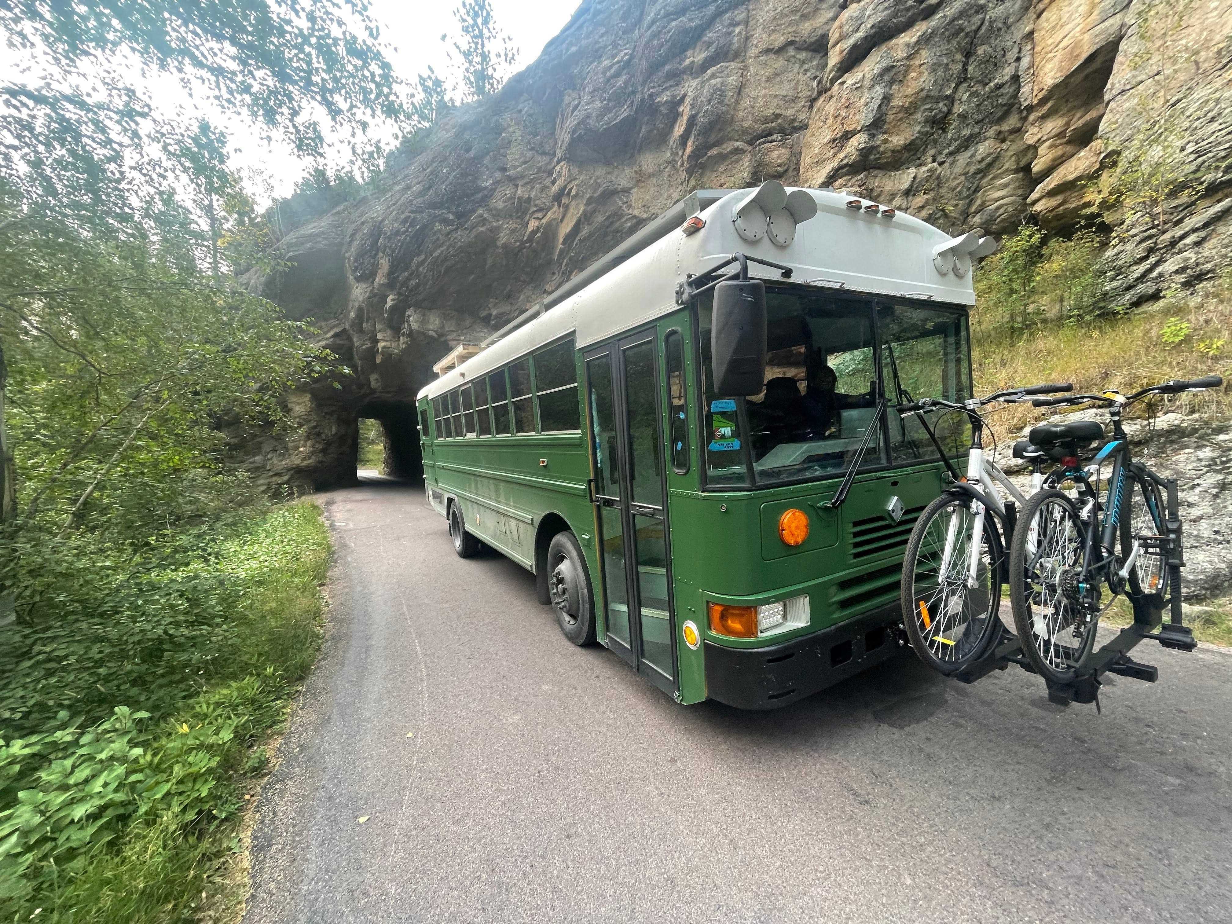 Schulbus auf der Straße mit geschnitztem Tunnel auf der Seite des Berges im Hintergrund