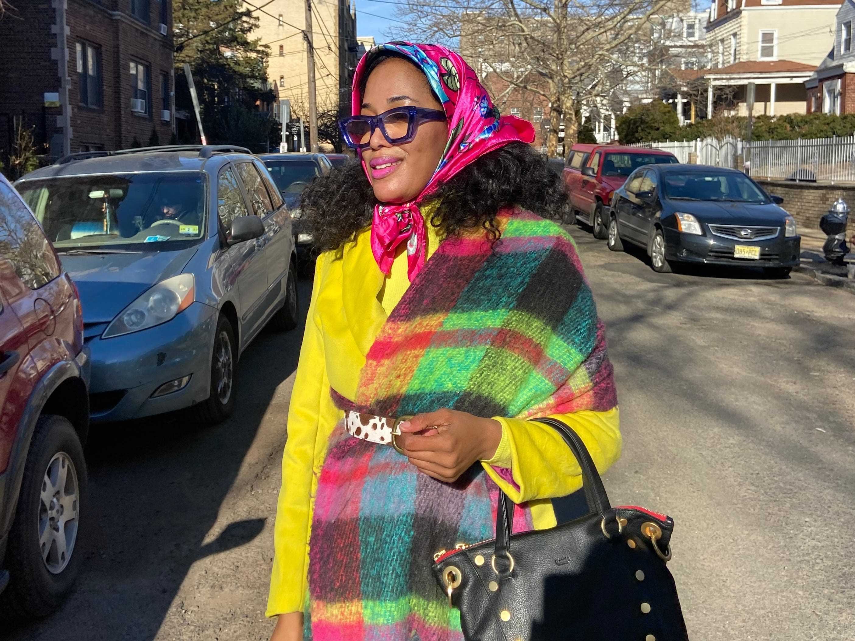 Sandra Okerulu trägt draußen einen farbenfrohen rosafarbenen Babuschka-Schal