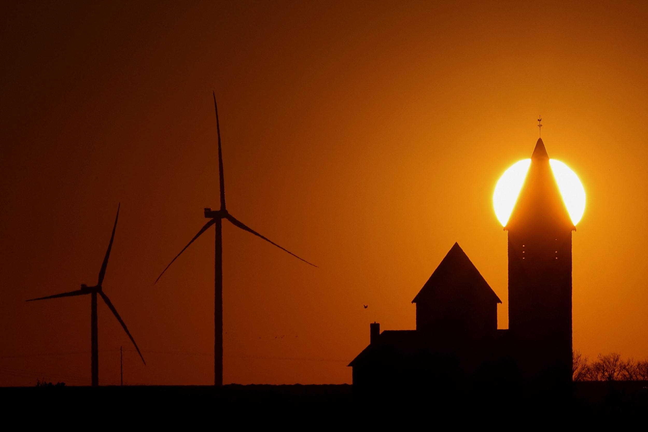 Windkraftanlagen und Kirche gegen Sonnenuntergang