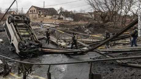 Ukrainische Streitkräfte gehen am Sonntag über eine zerstörte Brücke in Irpin, Ukraine. 