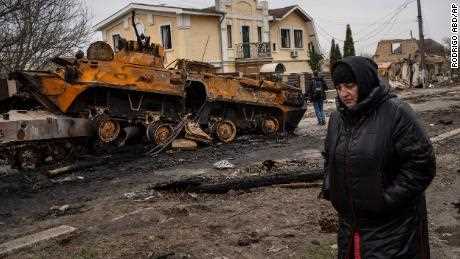 Eine Frau geht am 5. April neben einem zerstörten russischen Panzerfahrzeug in Bucha.