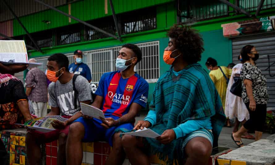 Junge Männer lesen eine Unabhängigkeitsbroschüre, in der sie zum Boykott des Referendums 2021 auf dem neukaledonischen Markt von Rivière Salée aufrufen