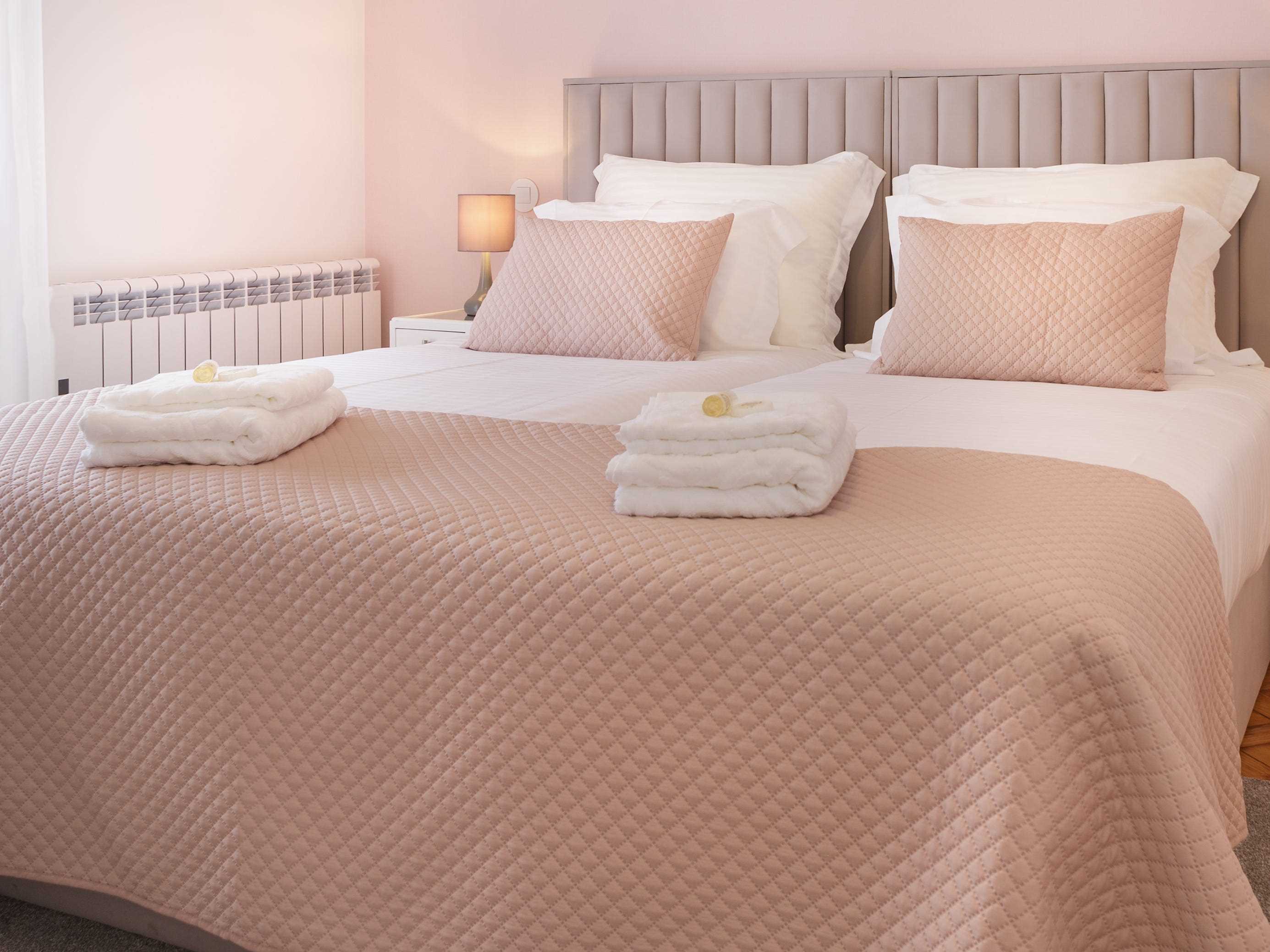 Rosa und weiße Laken auf Queensize-Bett im Zimmer mit rosafarbenen Wänden und weißen Vorhängen