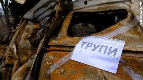 Auf einem Schild an einem ausgebrannten Auto steht „Leichen“.  auf Ukrainisch, Suchteams sagen, wo sie nach Leichen suchen sollen.