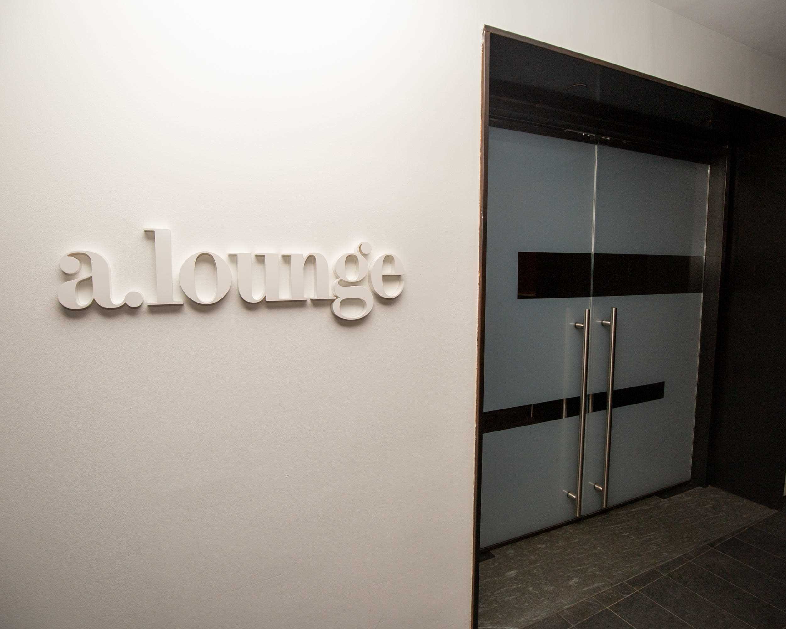 Ein Etikett an der Wand mit der Aufschrift „a.lounge“ neben einer Reihe von Türen.