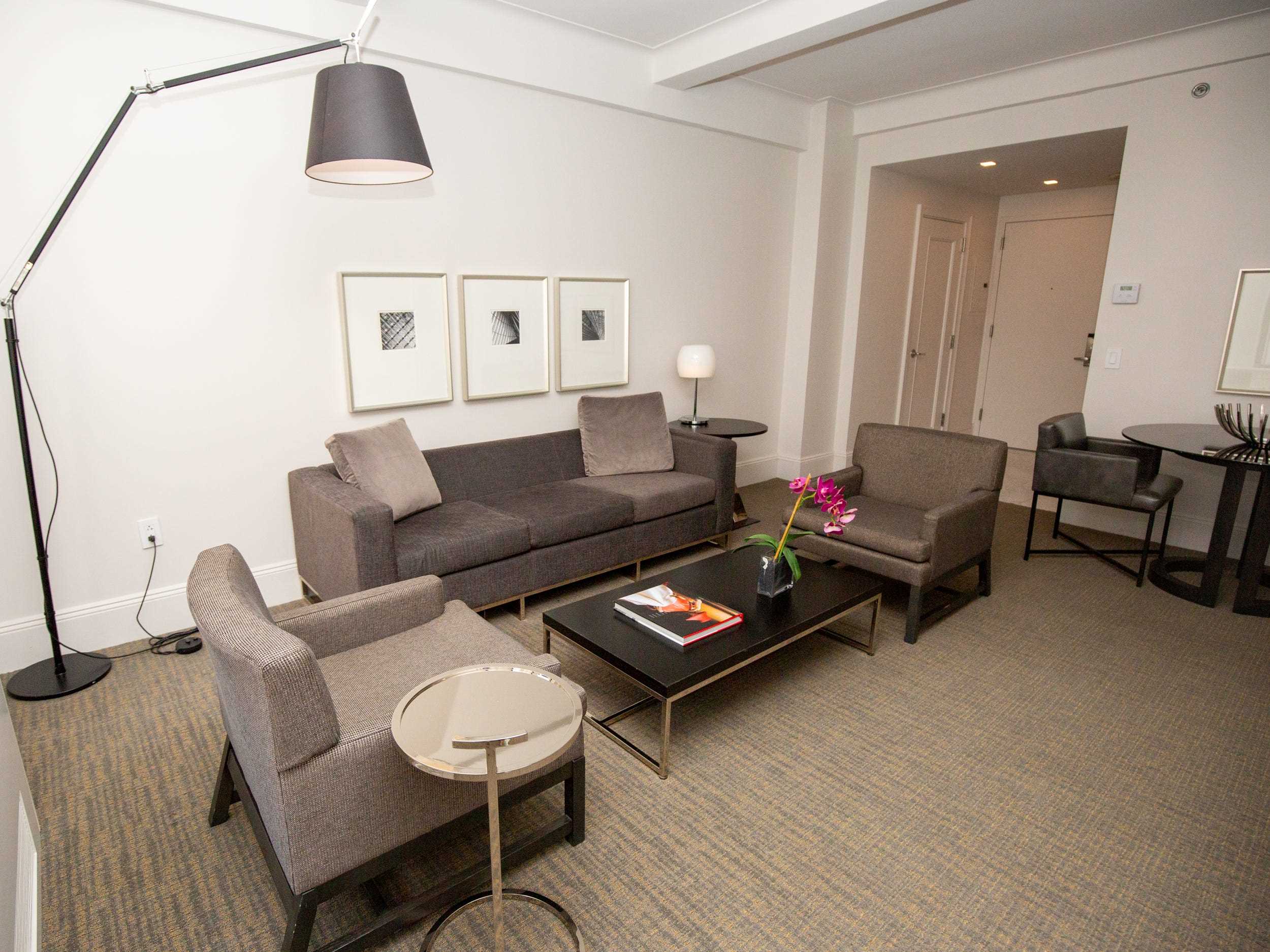 Das Wohnzimmer mit Sofas, Sitzen, Wanddekoration, einem Couchtisch und Lichtern in einer Suite im AKA Central Park.