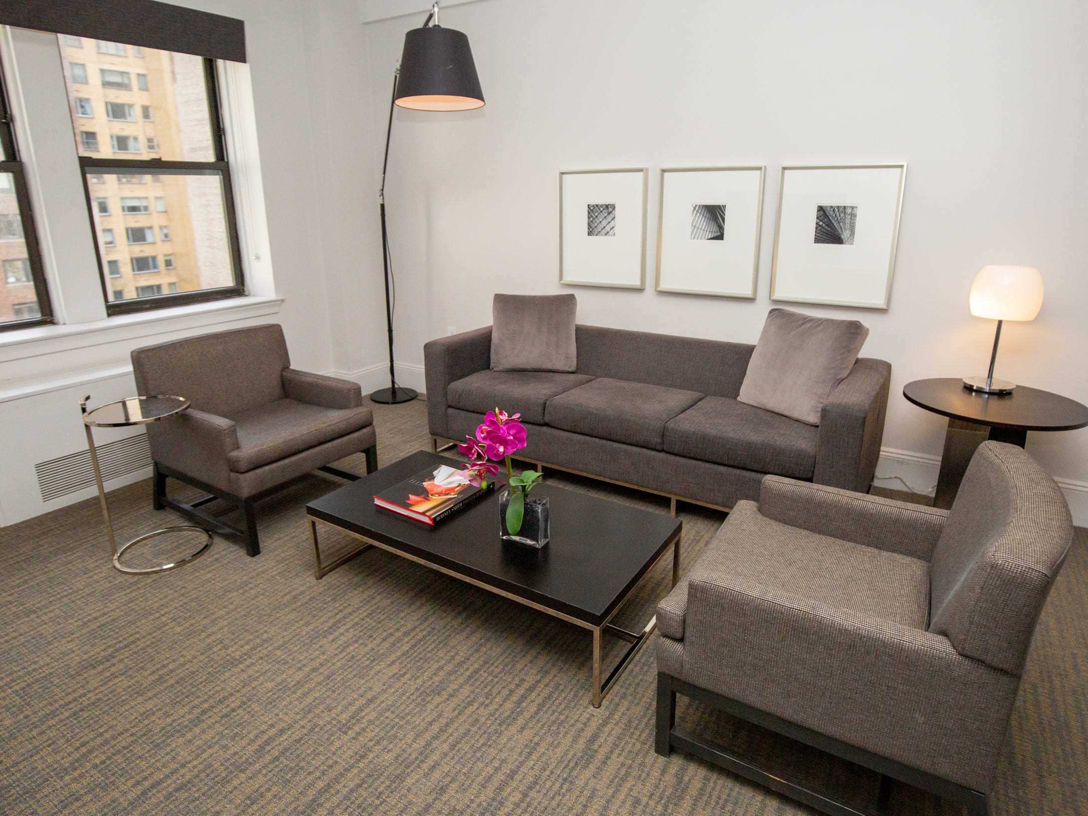 Das Wohnzimmer mit Sofas, Sitzen, Wanddekoration, einem Couchtisch und Lichtern in einer Suite im AKA Central Park.