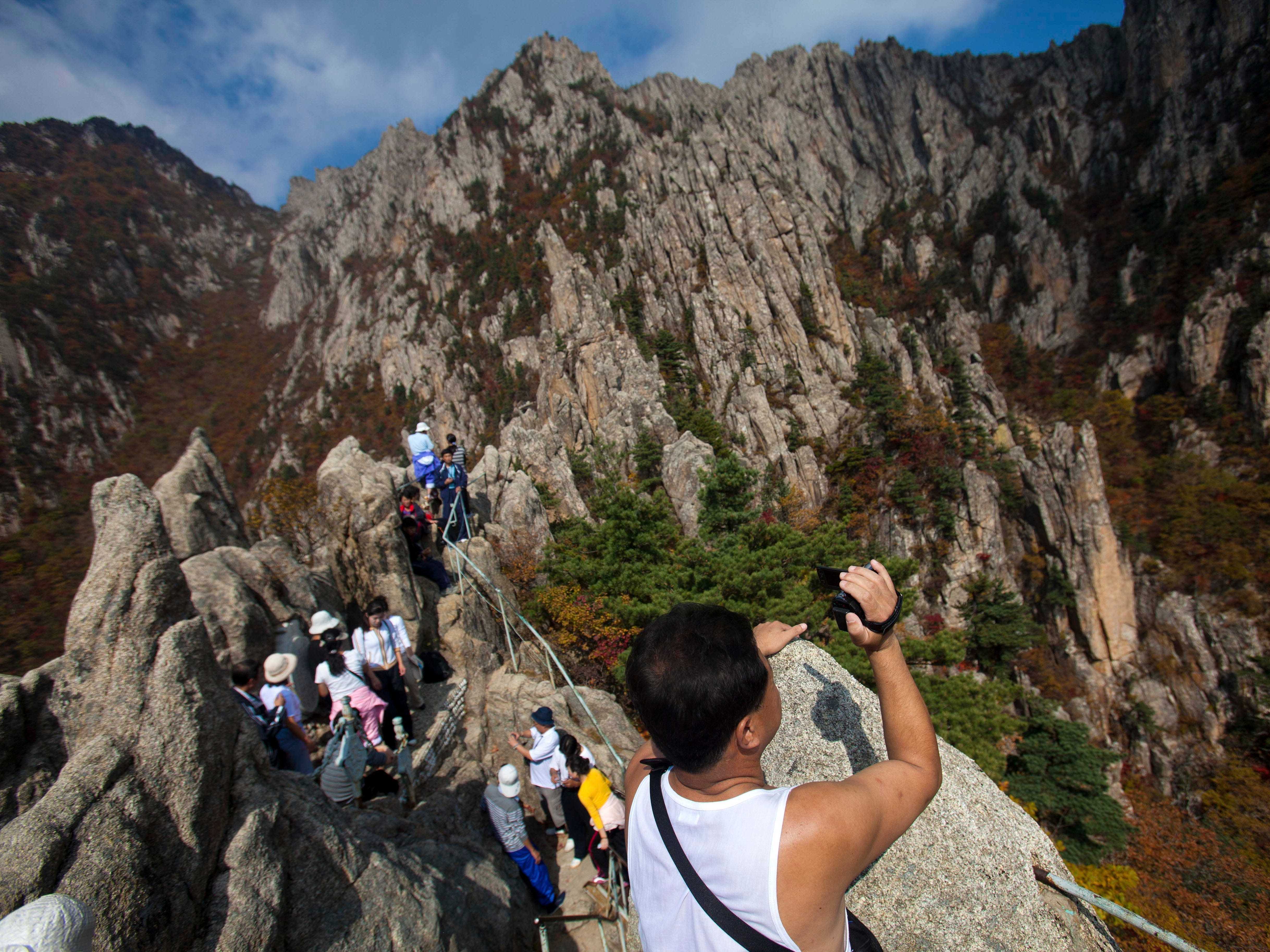 Auf diesem Foto vom Samstag, dem 8. Oktober 2011, nimmt ein Nordkoreaner ein Video der Landschaft auf, während er und andere Wanderer auf einen Gipfel des Mount Kumgang in Nordkorea klettern.