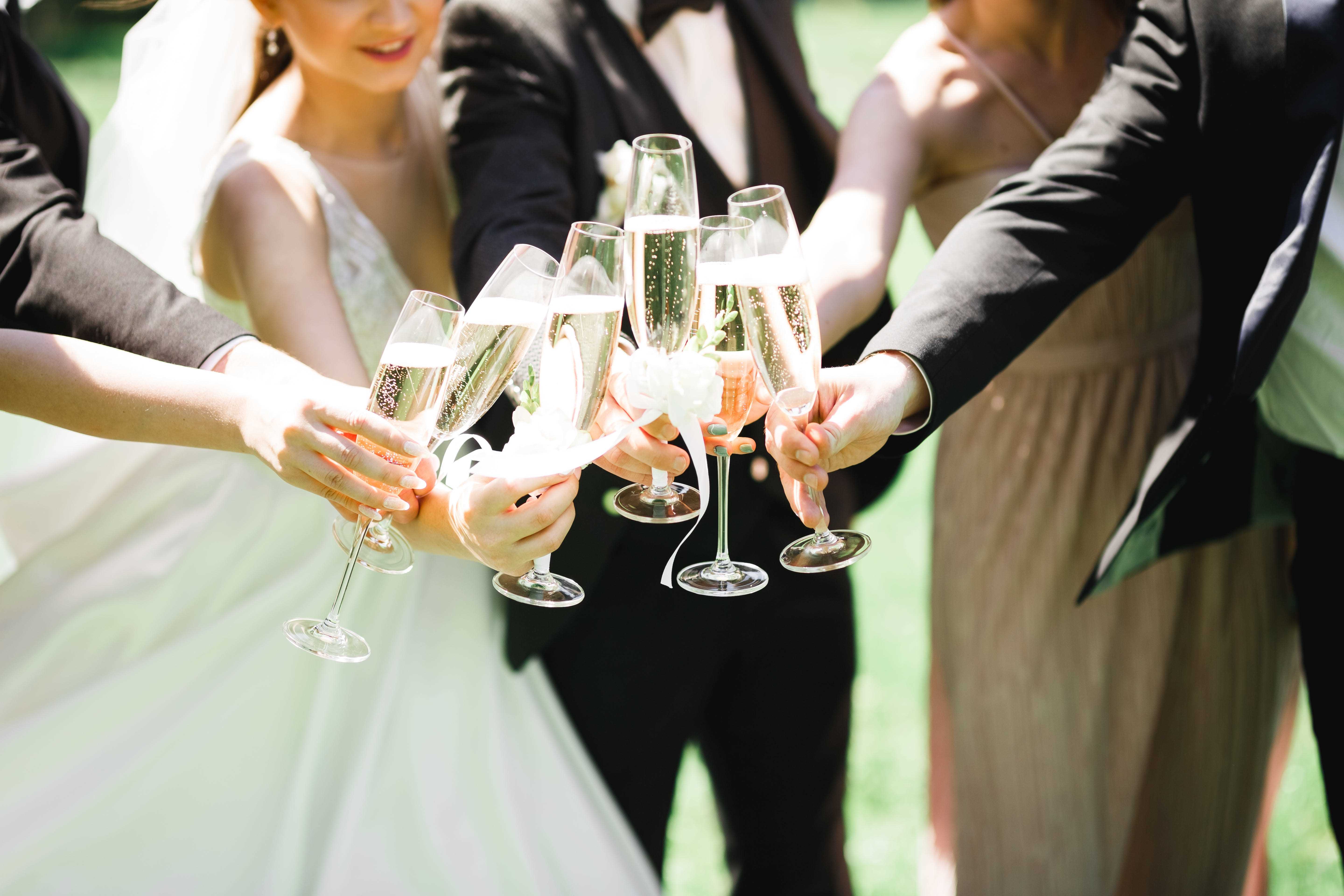 Ein Paar (Braut und Bräutigam) und ihre Gäste stoßen bei einer Hochzeit mit Champagner an