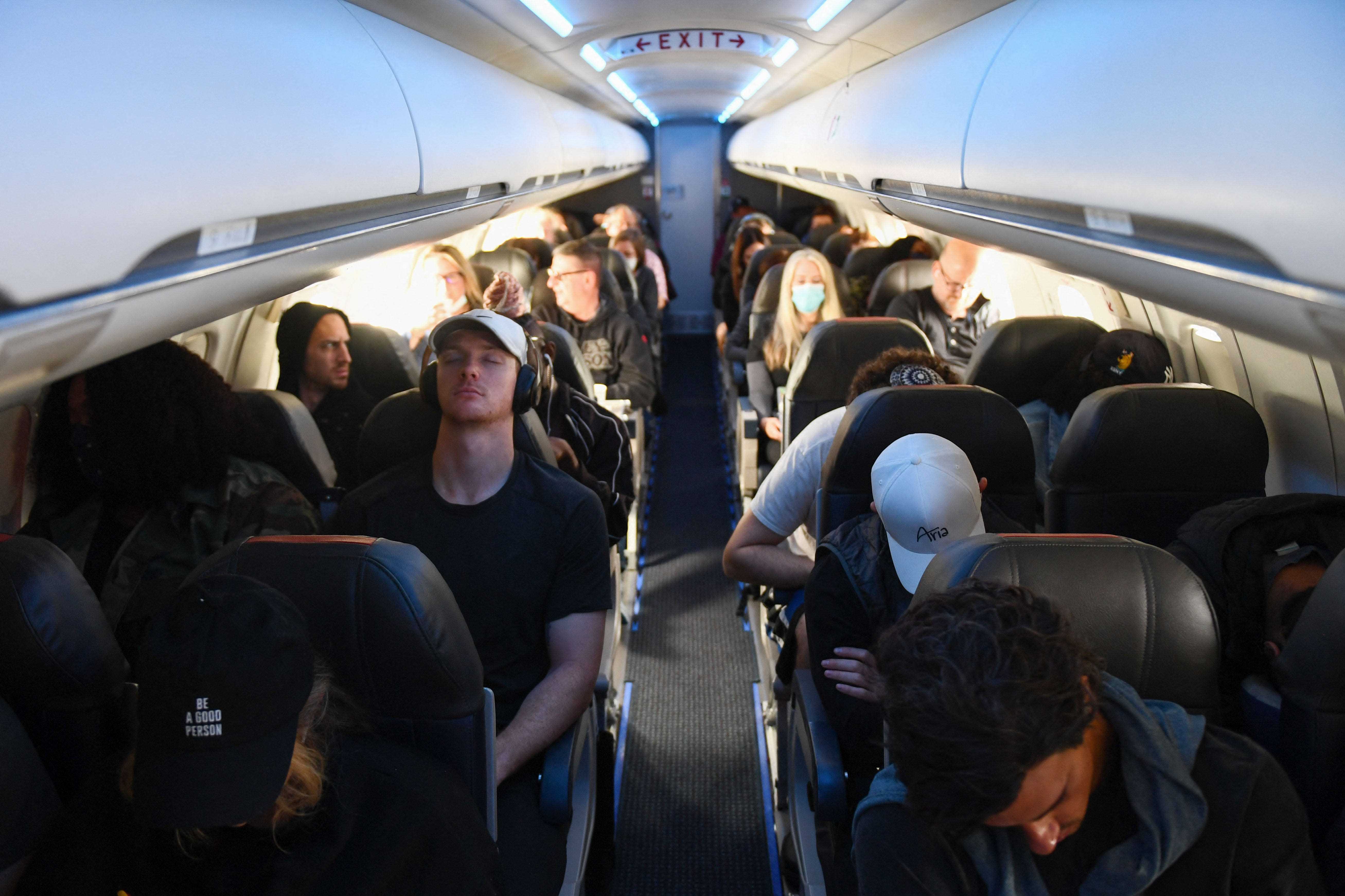 Fluggäste, von denen einige nach dem Ende der öffentlichen Verkehrsregeln von Covid-19 keine Gesichtsmasken tragen, sitzen am 19.