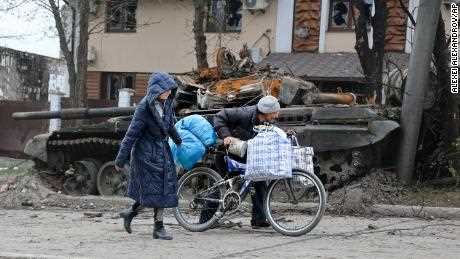 Lokale Zivilisten gehen an einem Panzer vorbei, der am 19. April bei schweren Kämpfen in Mariupol zerstört wurde.