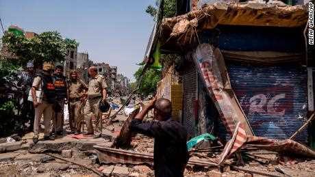 Polizisten stehen neben einem teilweise zerstörten Laden in der Gegend, in der am Samstag im nordwestlichen Viertel Jahangirpuri in Neu-Delhi, Indien, während einer hinduistischen religiösen Prozession kommunale Gewalt stattfand, Mittwoch, 20. 