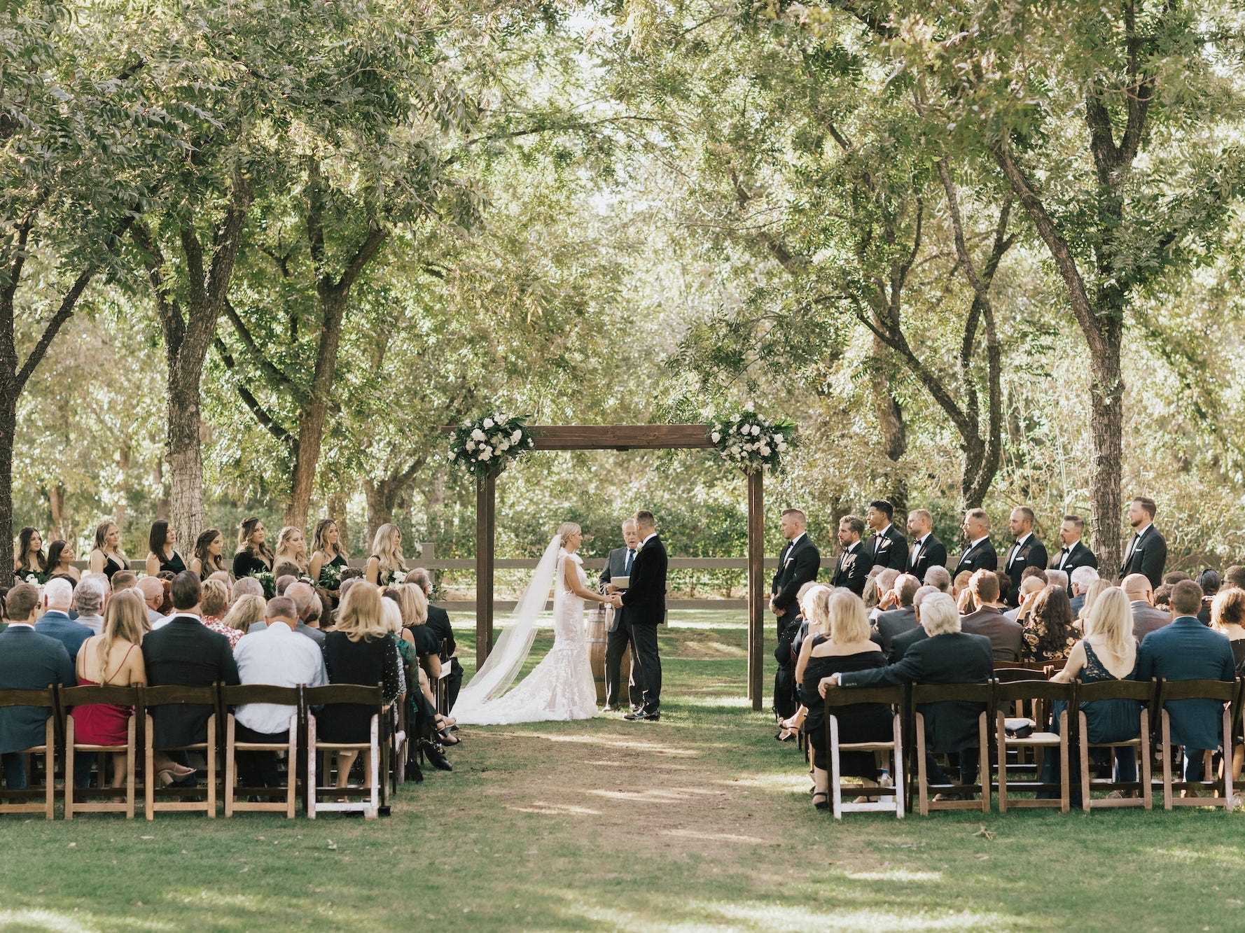 Eine Braut und ein Bräutigam stehen während ihrer Trauung unter einem Bogen.