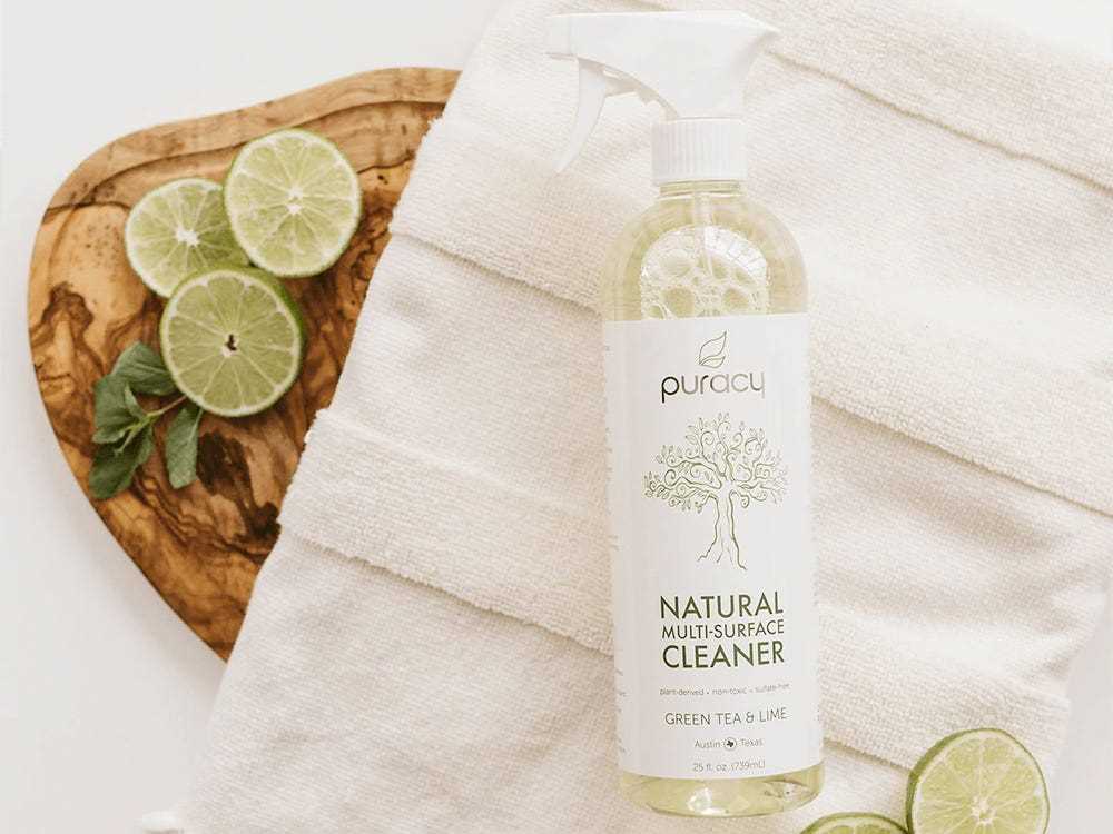 Eine Flasche Puracy-Reiniger liegt auf einem Tuch neben einigen Limetten, den besten natürlichen Reinigungsmitteln im Jahr 2022.