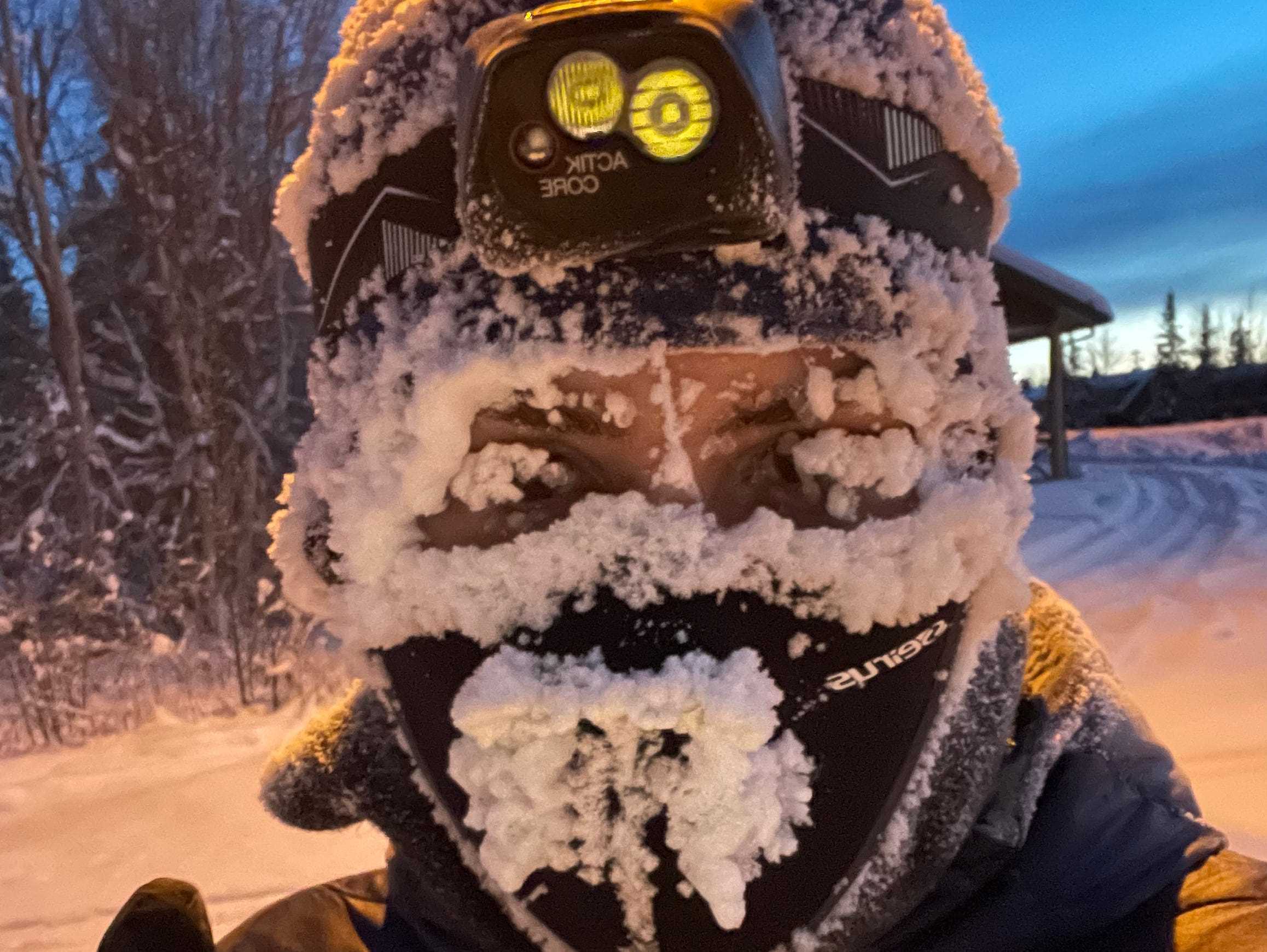 Person mit Wintergesichtsausrüstung und einer Stirnlampe, die in Kanada mit Frost und Schnee bedeckt ist