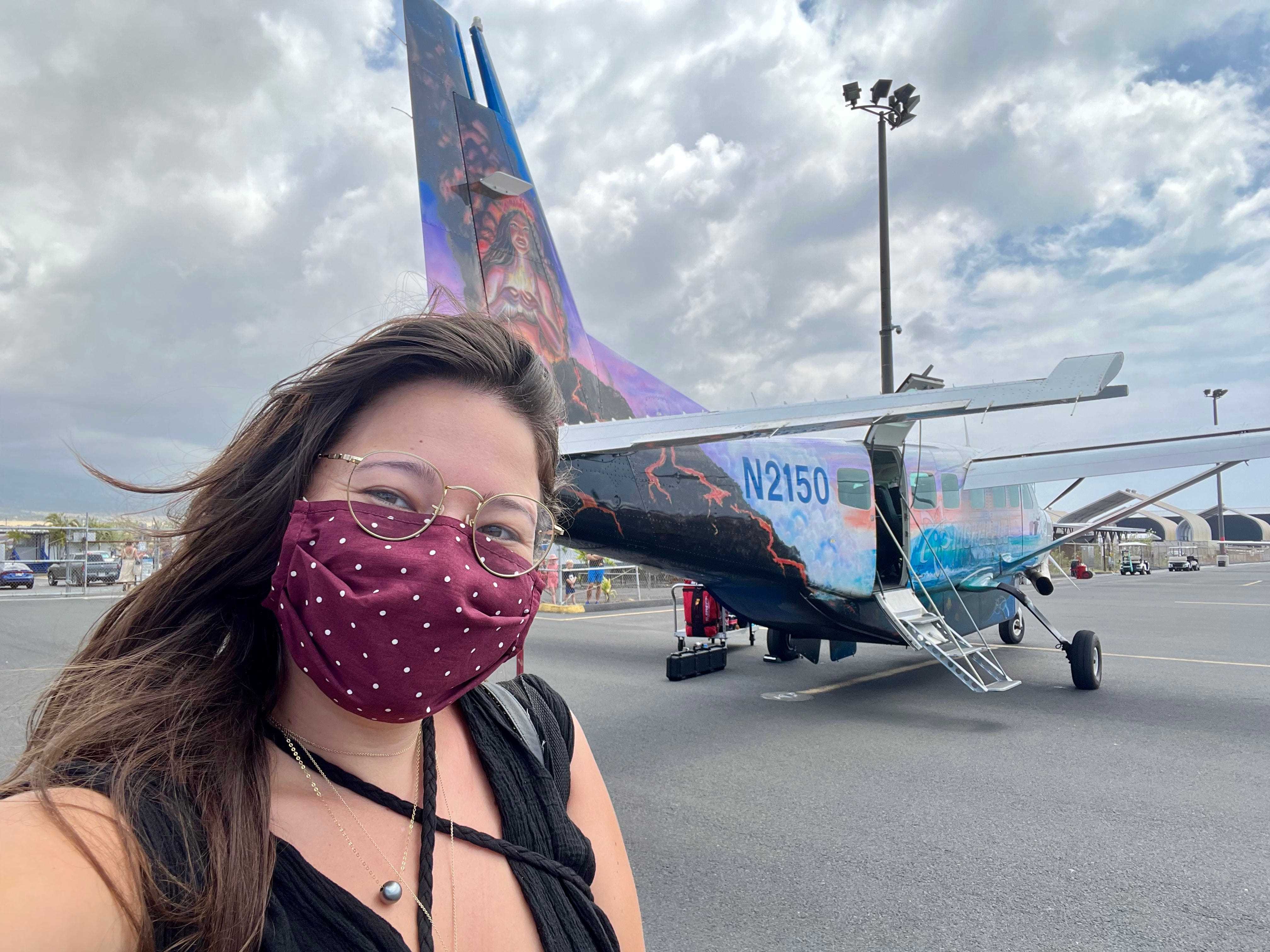 Der Schriftsteller trägt eine Maske und macht ein Selfie vor dem kleinen Pendlerflugzeug mit farbenfrohen Kunstwerken