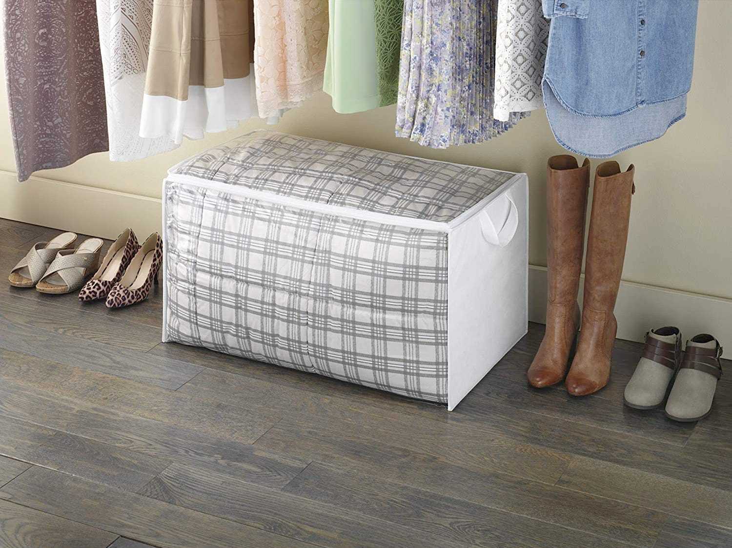 Ein Deckenhalter sitzt in einem Schrank neben Schuhen und unter darüber hängenden Kleidungsstücken.