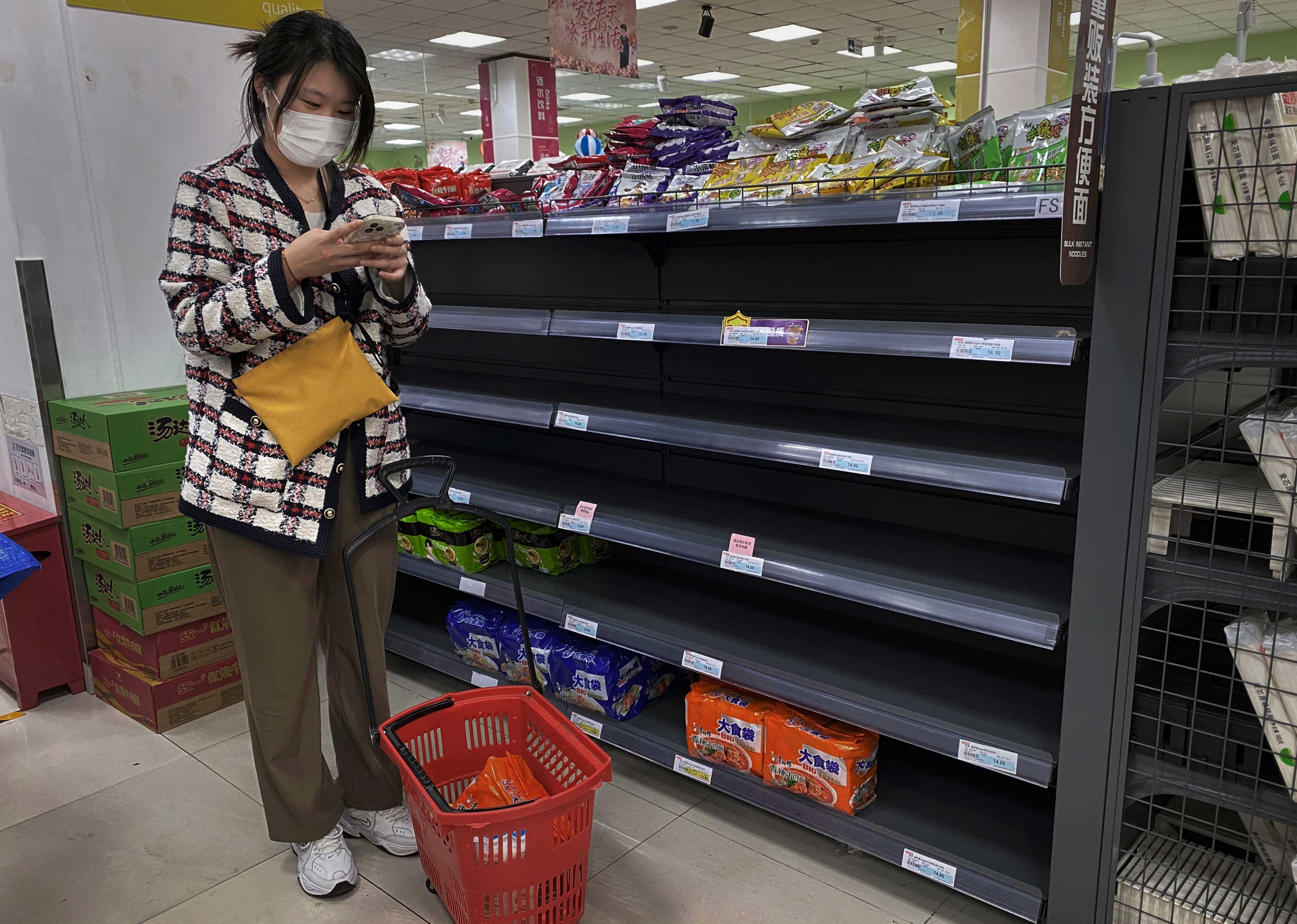 Eine Frau steht am 25. April 2022 in Peking, China, neben leeren Regalen im Gang für Fertignudeln in einem Supermarkt im Bezirk Chaoyang.
