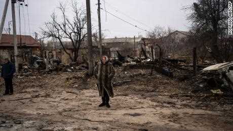 Eine Frau steht am Dienstag in einem zerstörten Viertel von Bucha.