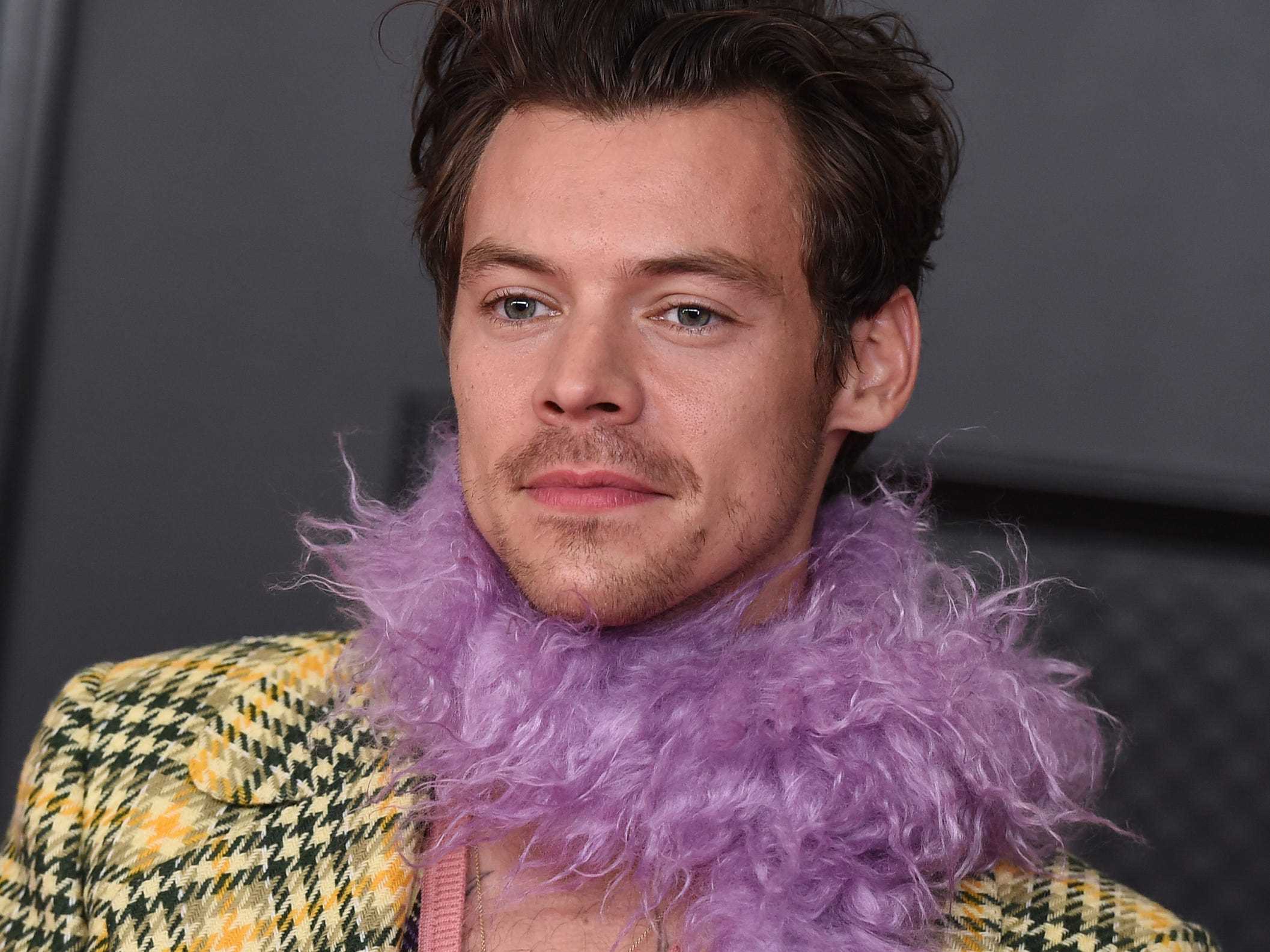 Harry Styles trägt bei den Grammys 2021 eine karierte Jacke und eine lila Federboa.