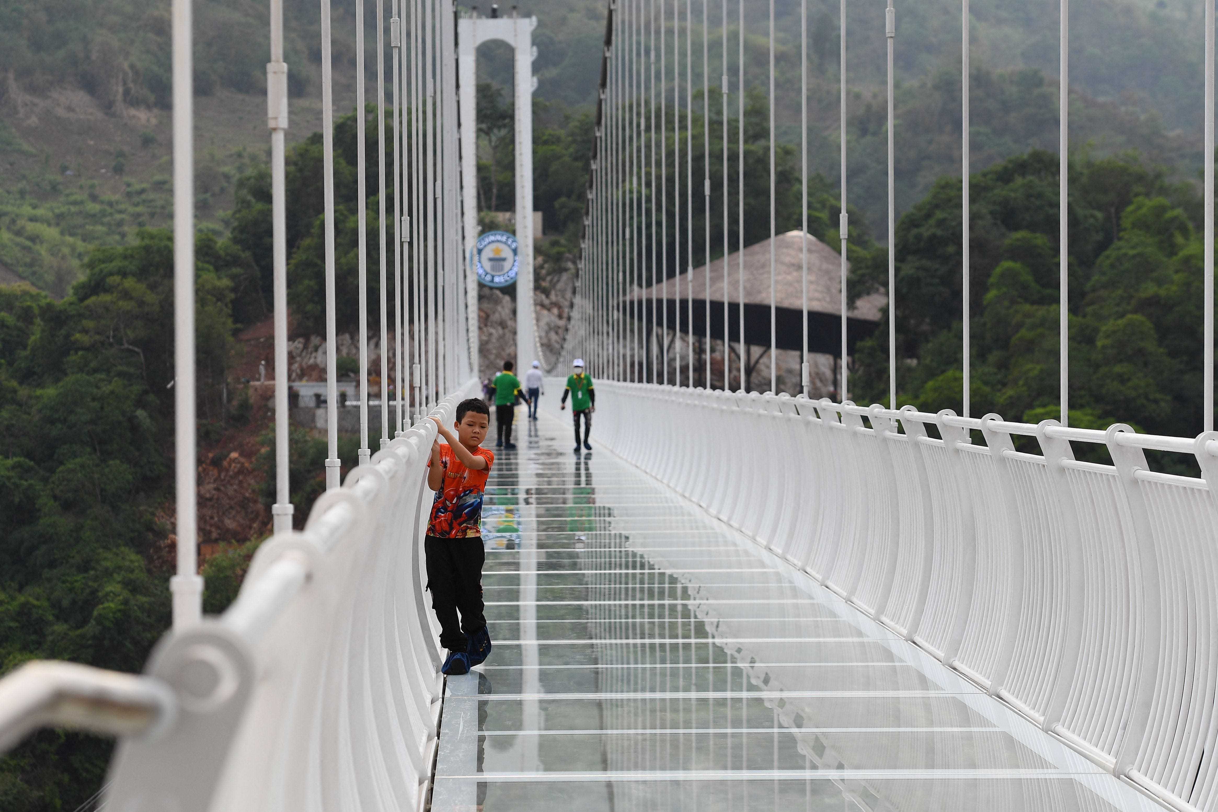 Ein Kind klammert sich an das Geländer der Glasbrücke Bach Long im Distrikt Moc Chau in der vietnamesischen Provinz Son La