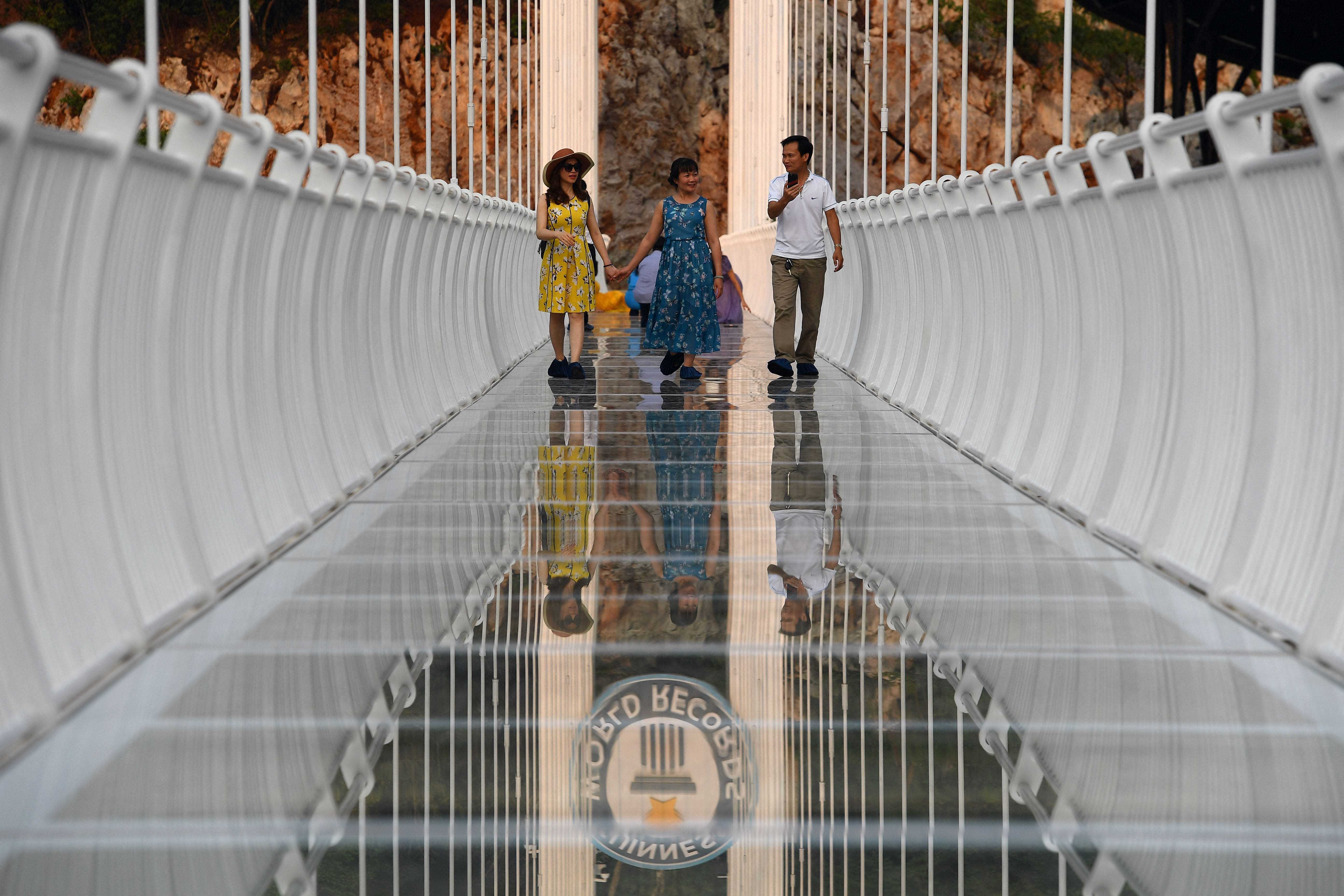 Menschen gehen auf der Glasbrücke Bach Long im Distrikt Moc Chau in der vietnamesischen Provinz Son La