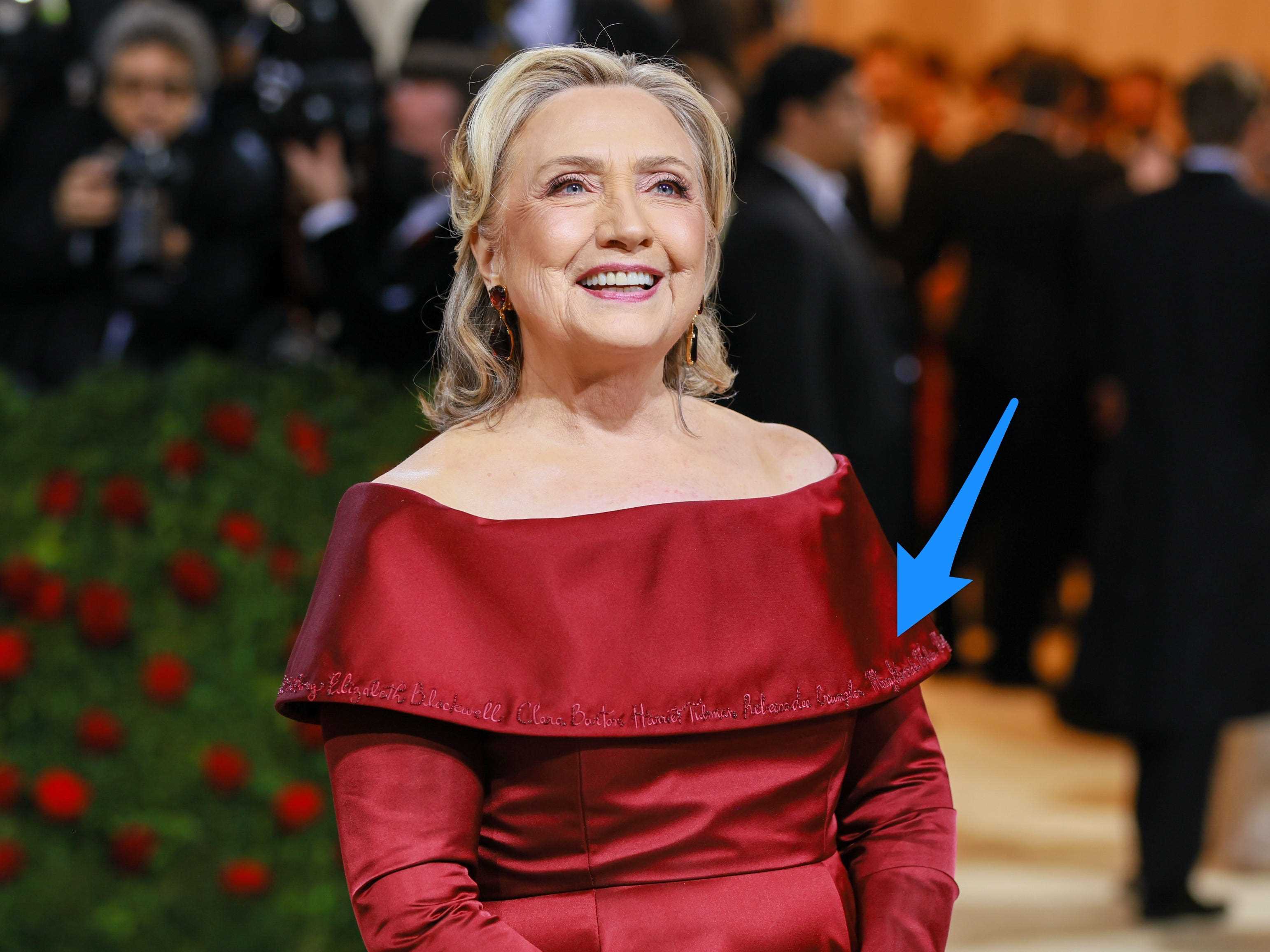Hillary Clinton bei der Met Gala 2022 mit einem Pfeil, der auf ihr Kleid zeigt.