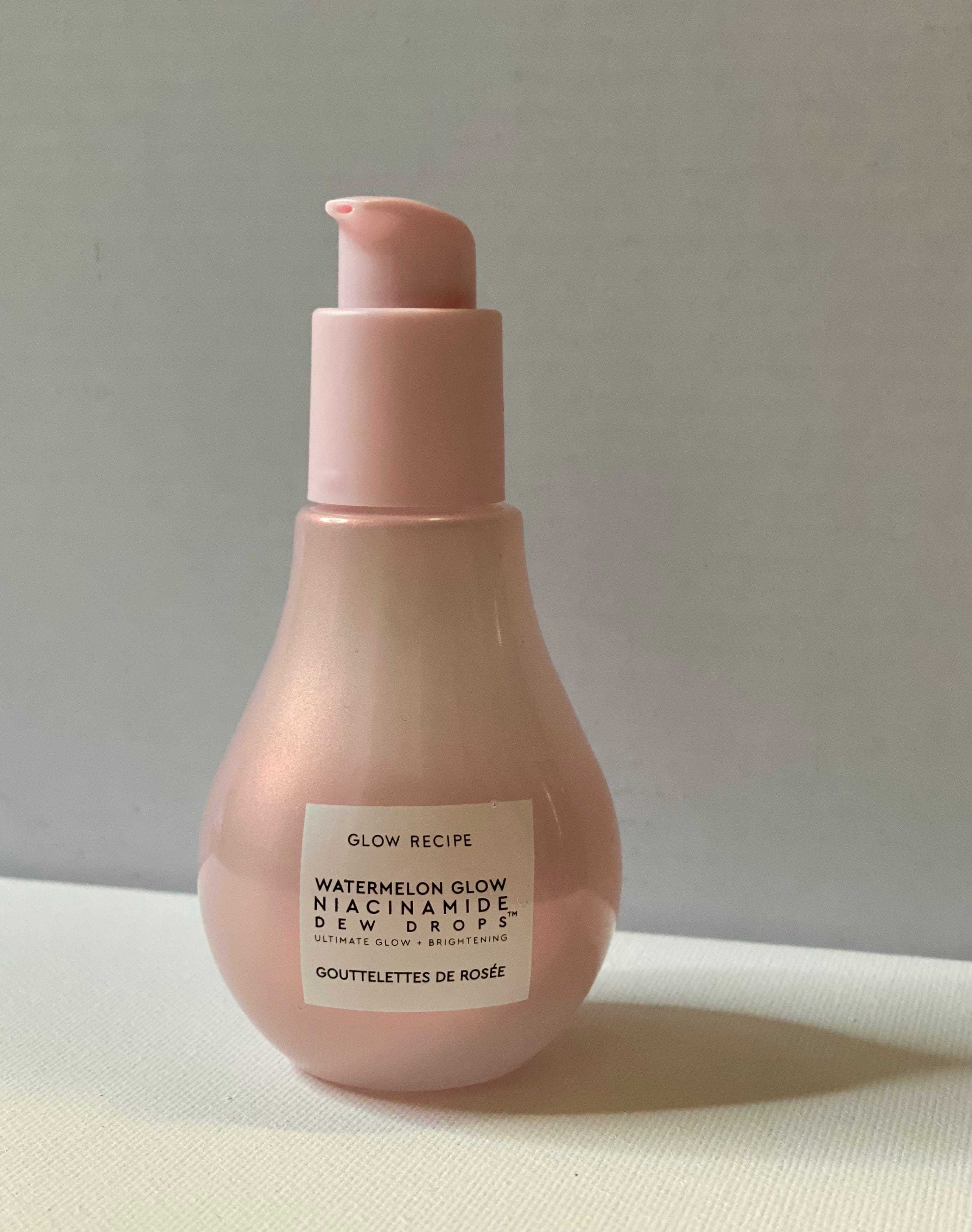 Glow-Rezept Niacinamid-Tautropfen in einer rosa birnenförmigen Flasche mit einer Pumpe vor einem weißen Hintergrund
