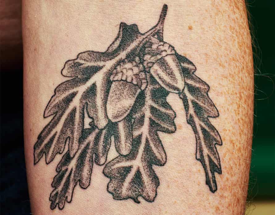 Der nackte Arm eines Mannes mit einem Eichenblatt-Tattoo