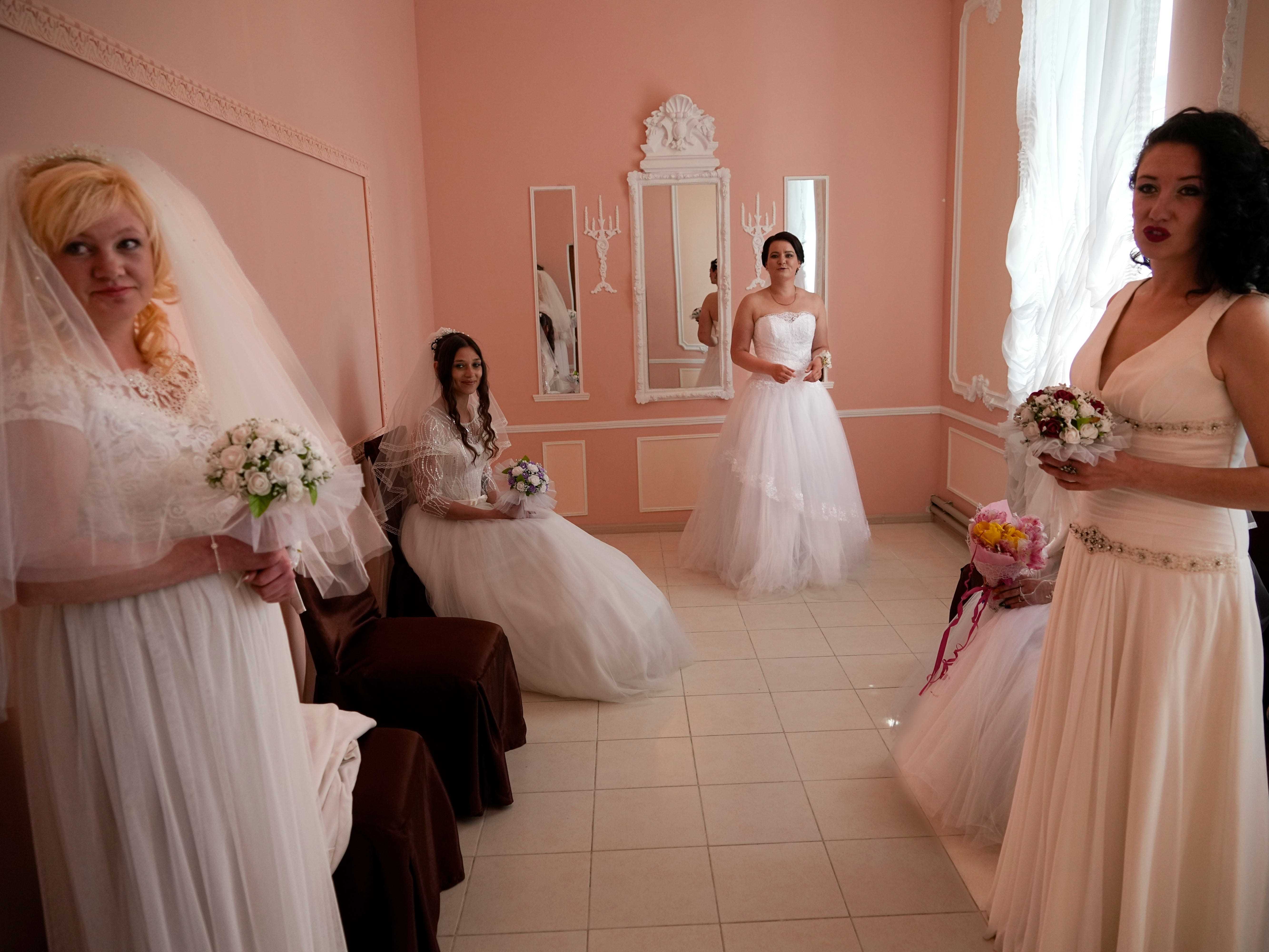 Vier Frauen in Brautkleidern posieren für ein Foto.