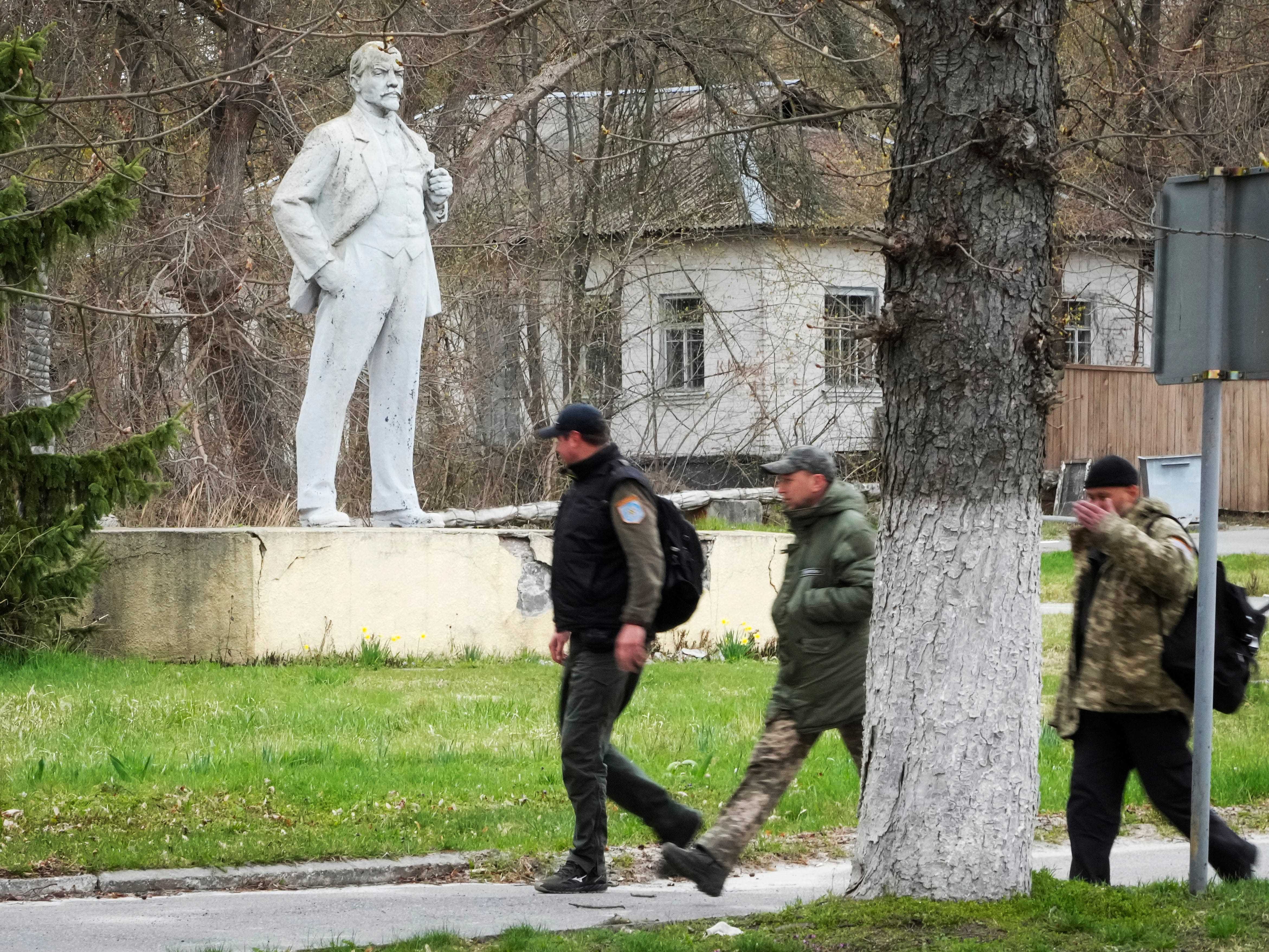 Menschen gehen an einer Statue von Wladimir Lenin vorbei.