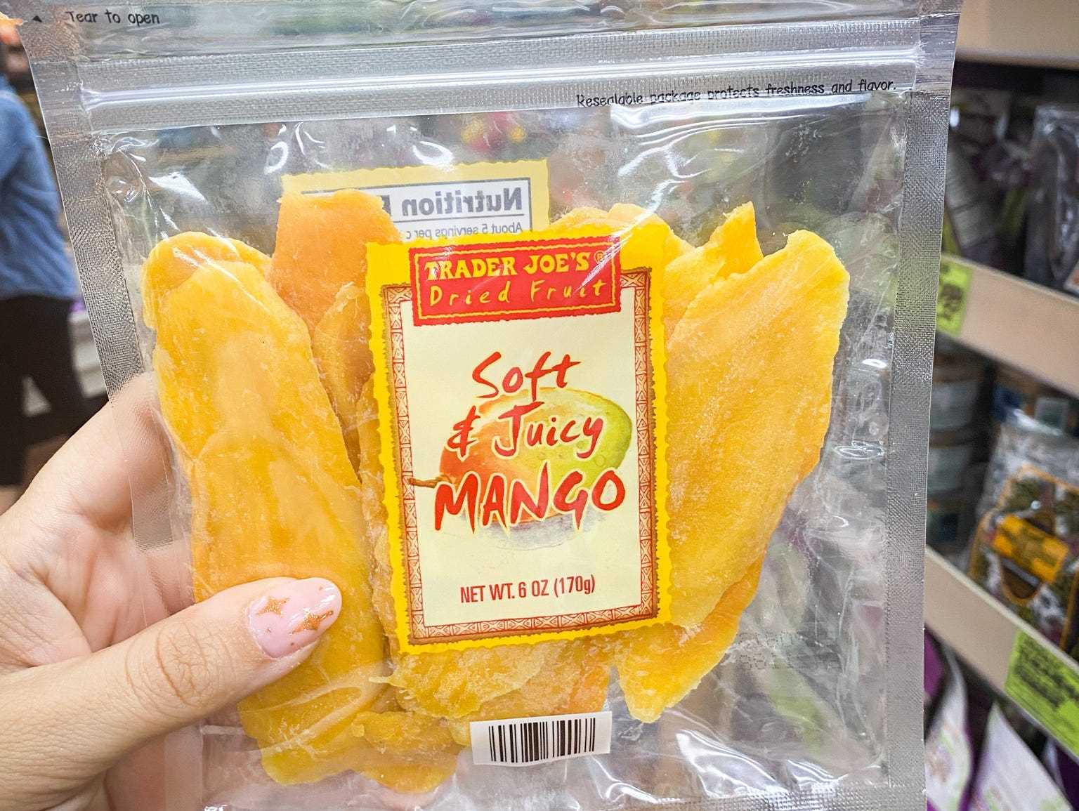 Hand, die eine Packung getrockneter Mango in einem Gang bei Trader Joes hält