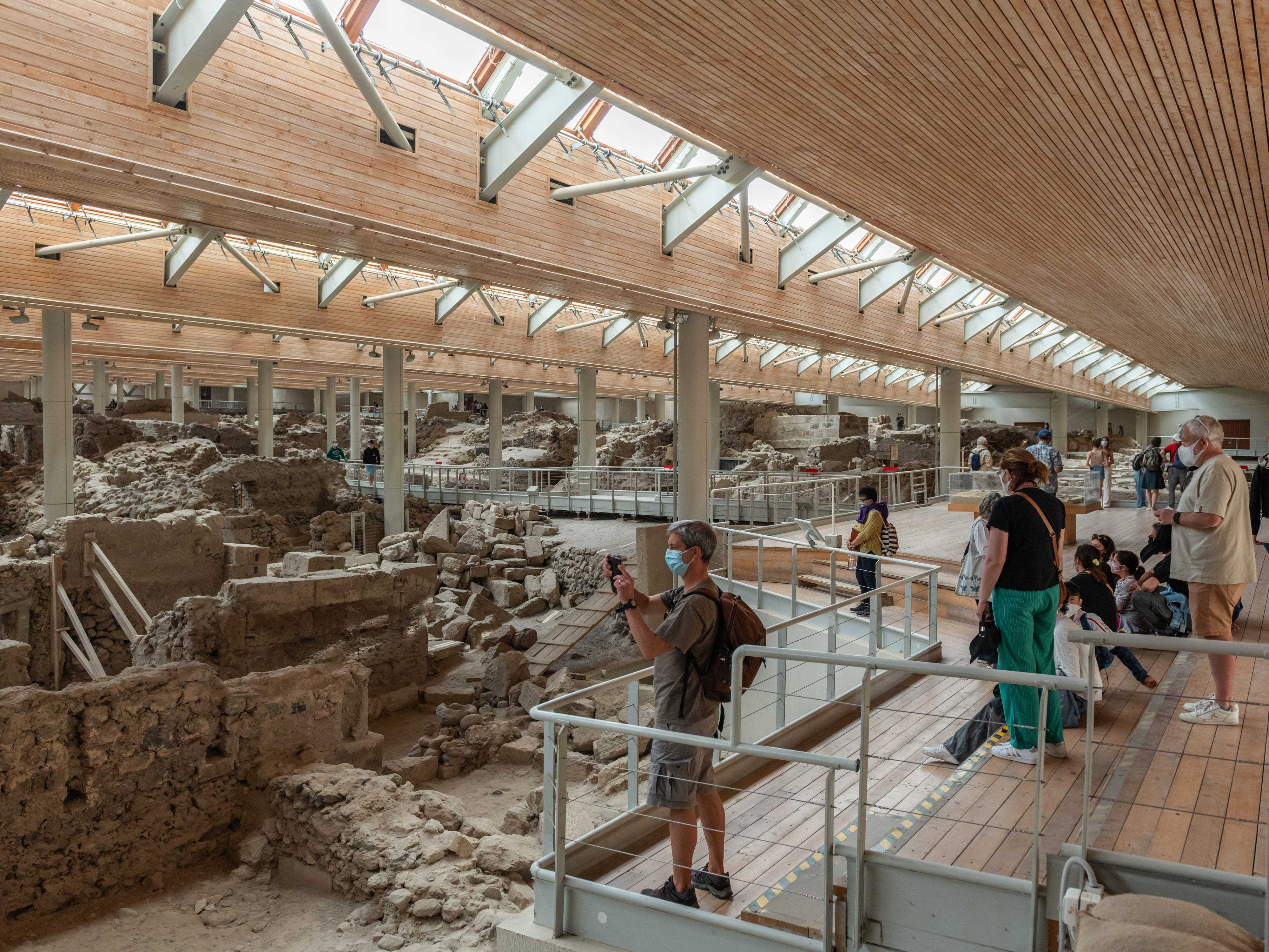 Besucher, die sich die Ausstellung ansehen und im Museumsbereich mit griechischen Ruinen fotografieren