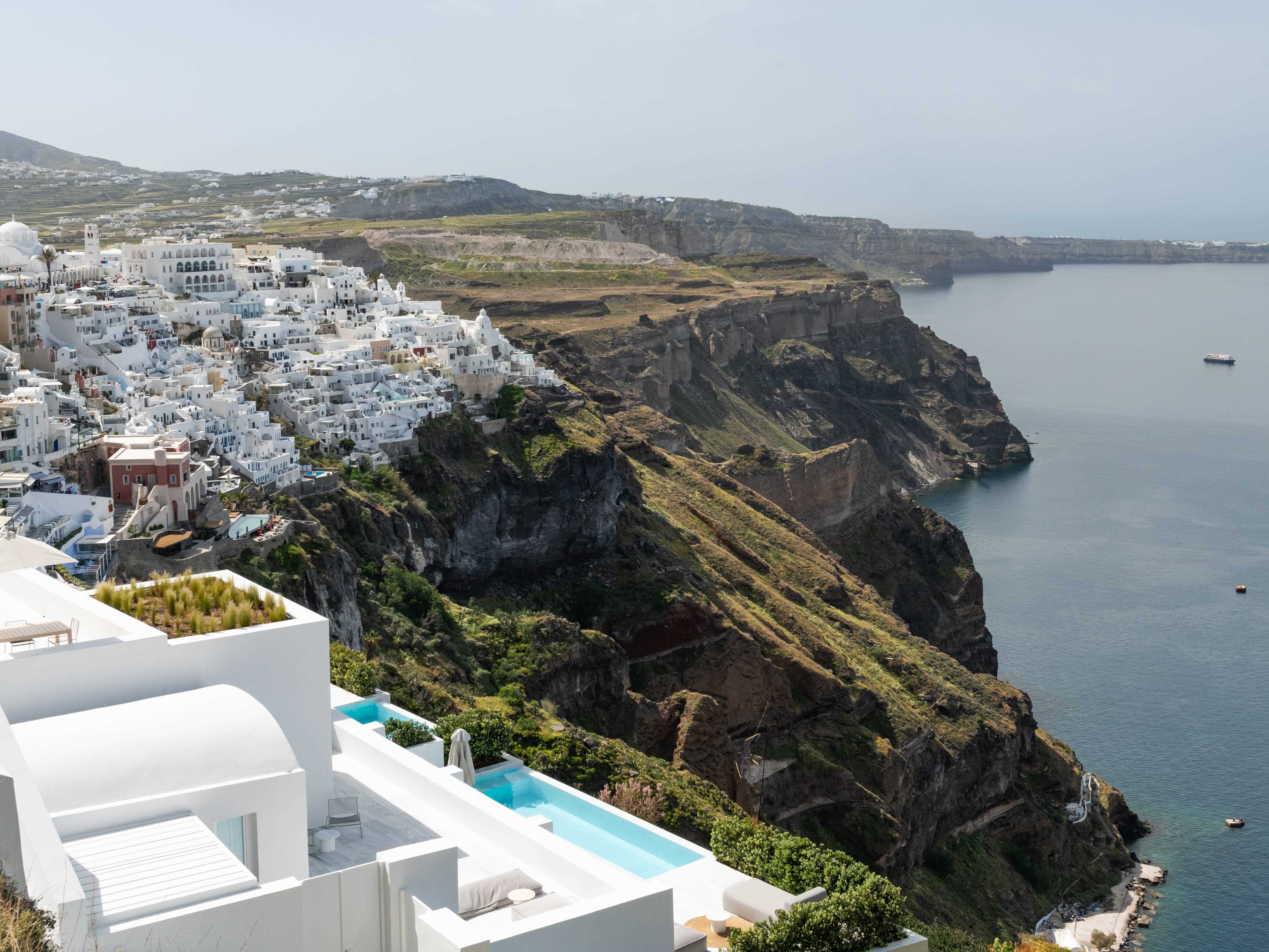 Blick auf weiß getünchte griechische Gebäude auf Hügeln und an der Küste und Blick auf das Meer