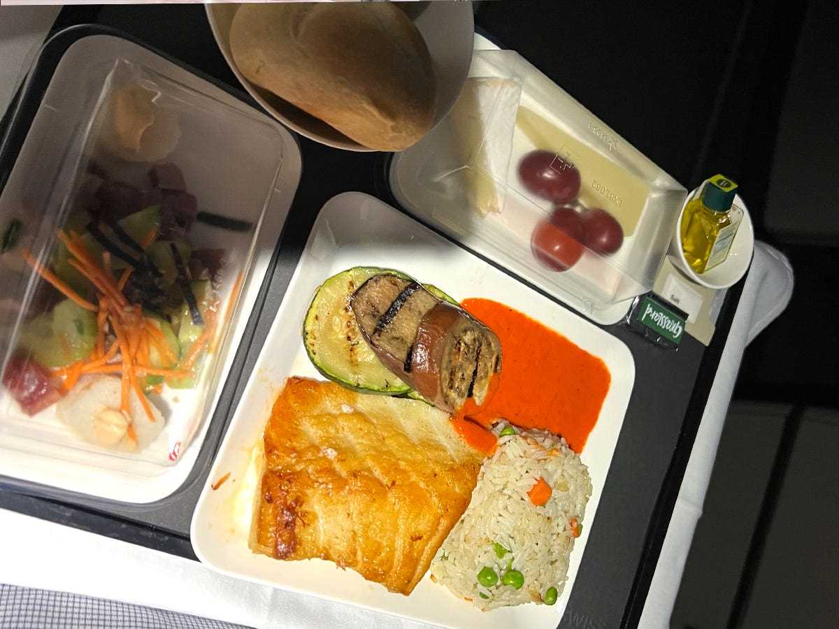 Ein Tablett mit Essen in einem Flugzeug mit Fisch, Reis und Trauben