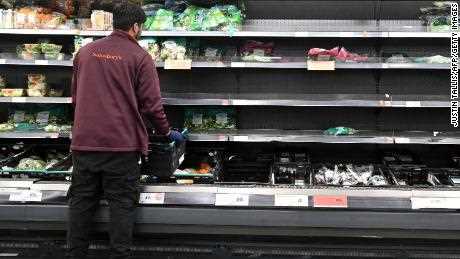 Ein Arbeiter füllt am 7. September 2021 leere Regale mit Kopfsalat und Salatblättern in einem Supermarkt in Sainsbury in London auf. 