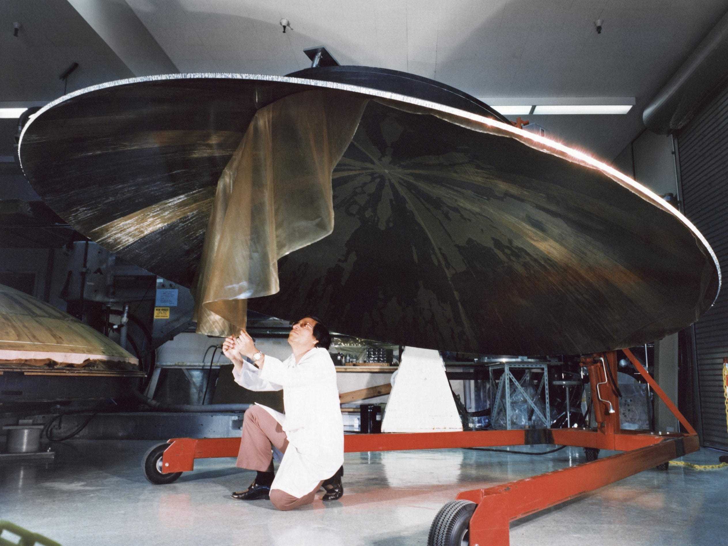 Dieses Archivfoto zeigt einen Ingenieur, der an der Konstruktion einer großen, schüsselförmigen Voyager-Hochleistungsantenne arbeitet.  Das Bild wurde am 9. Juli 1976 aufgenommen.