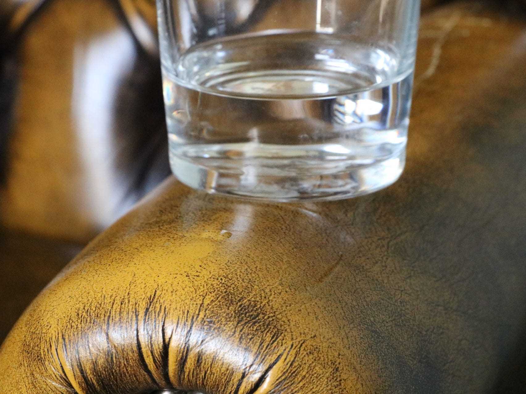 Ein Glas Wasser auf der Armlehne eines Ledersessels.