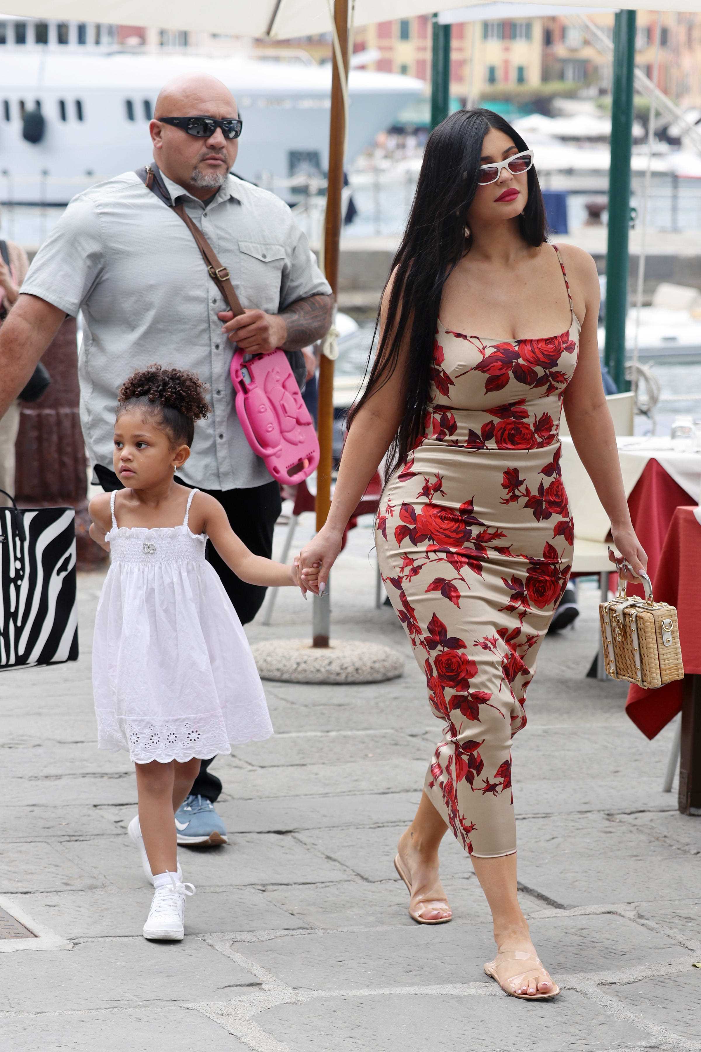Kylie Jenner in einem geblümten Kleid hält Händchen mit ihrer Tochter