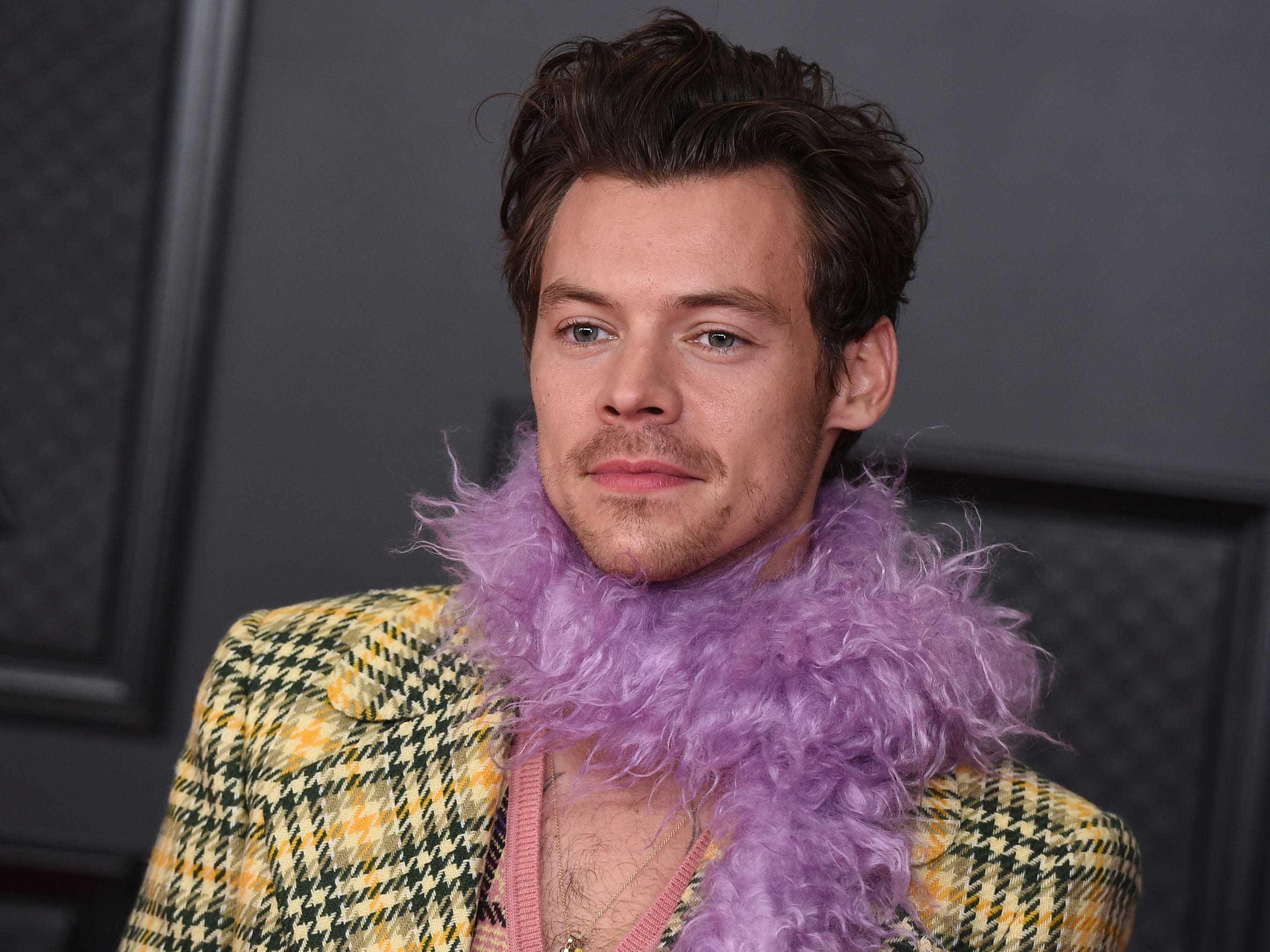 Harry Styles trägt bei den Grammys 2021 eine karierte Jacke und eine lila Federboa.