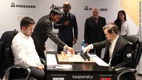 Pragg bewegt eine Schachfigur bei einem Match zwischen Ian Nepomniachtchi (links) und Magnus Carlsen (rechts) bei der FIDE-Schachweltmeisterschaft auf der EXPO 2020 Dubai am 7. Dezember 2021.