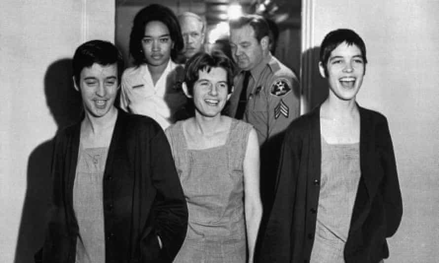 Auf einem Schwarz-Weiß-Foto verlassen drei Frauen lachend und lächelnd einen Raum.