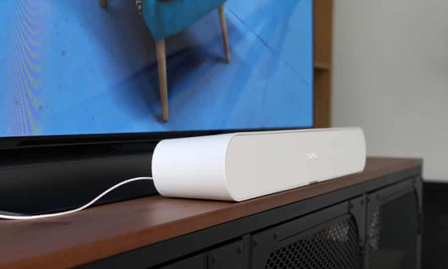 Die Sonos Ray Soundbar aus einem Winkel betrachtet, auf einem TV-Schrank vor einem Fernseher sitzend.