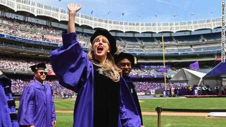 Taylor Swift winkt Absolventen während der Eröffnungszeremonie der New York University für den Jahrgang 2022 zu.