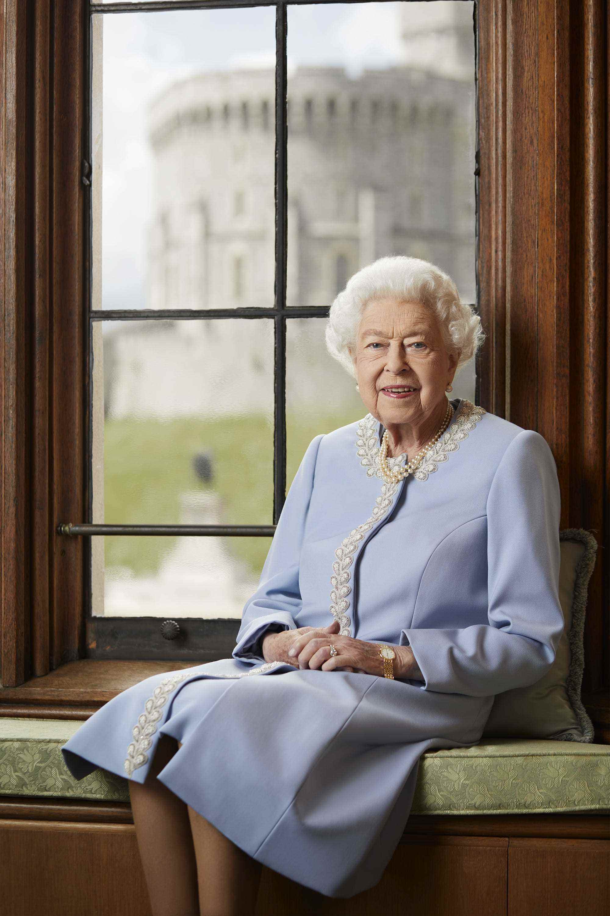 Königin Elizabeth sitzt für ein königliches Porträt auf einer Bank.