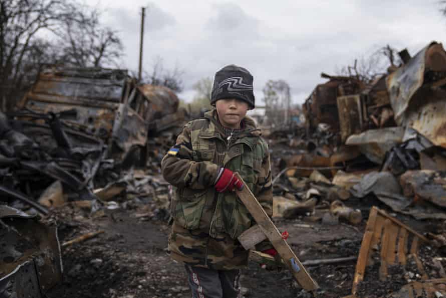Der siebenjährige Yehor hält ein Spielzeuggewehr neben zerstörten russischen Militärfahrzeugen in der Nähe von Tschernihiw in der Ukraine.