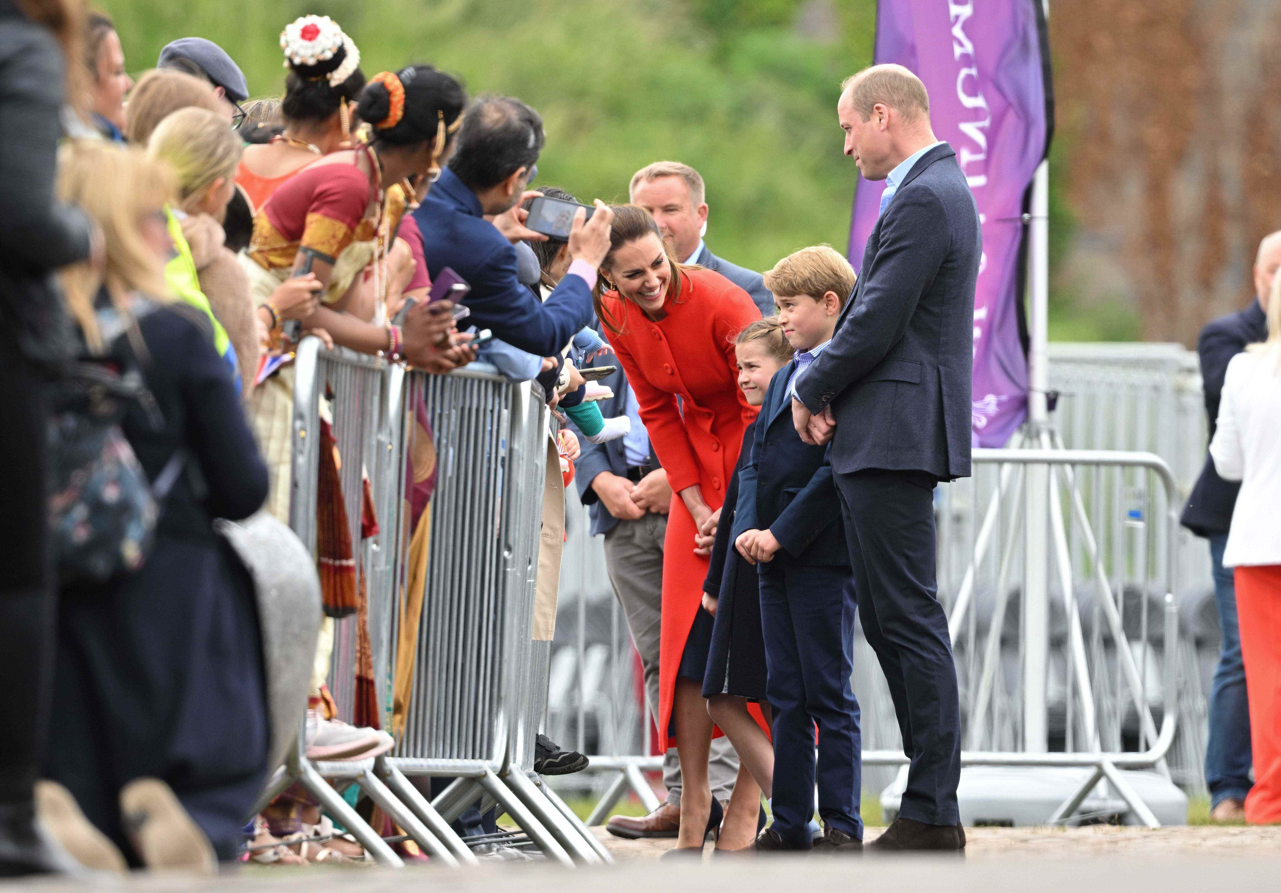 Kate Middleton bückt sich, um mit ihren Kindern zu sprechen, während Prinz William neben ihnen steht