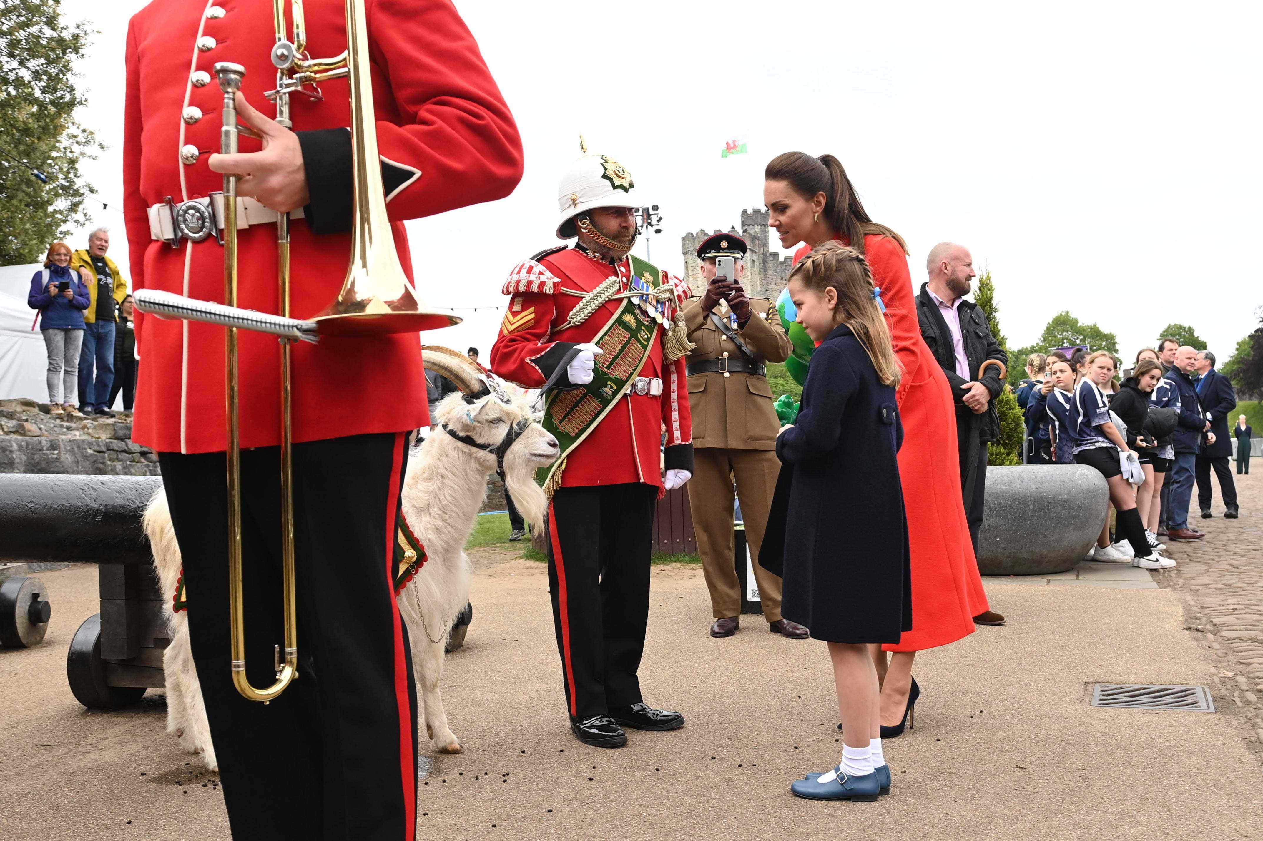 Prinzessin Charlotte und Kate Middleton stehen vor einer Ziege und Bandmitgliedern