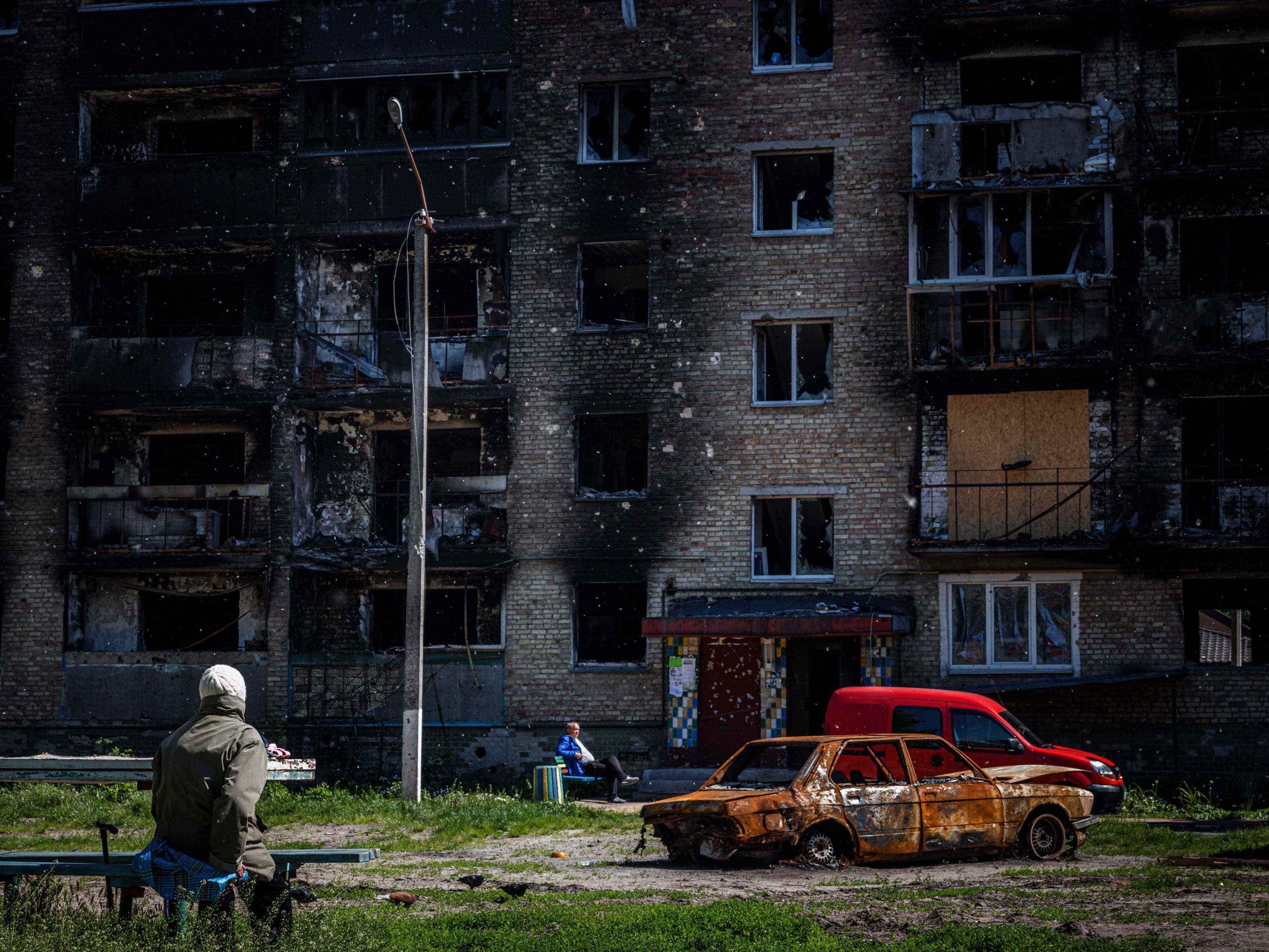 Anwohner sitzen am 31. Mai 2022 inmitten der russischen Invasion in der Ukraine neben einem beschädigten Wohnhaus in der Stadt Irpin bei Kiew.