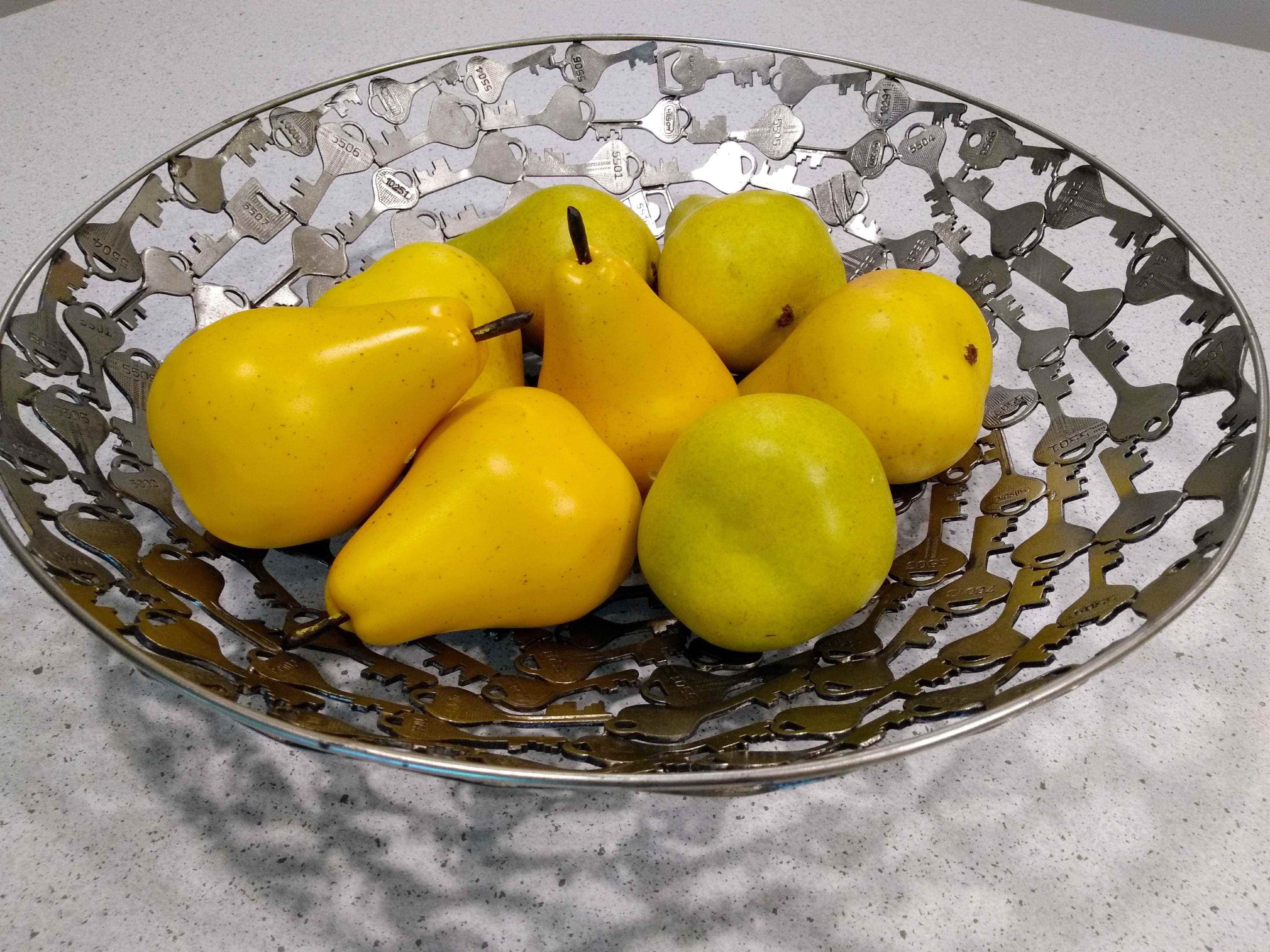 Gelbe Plastikbirnen in einer silbernen Obstschale